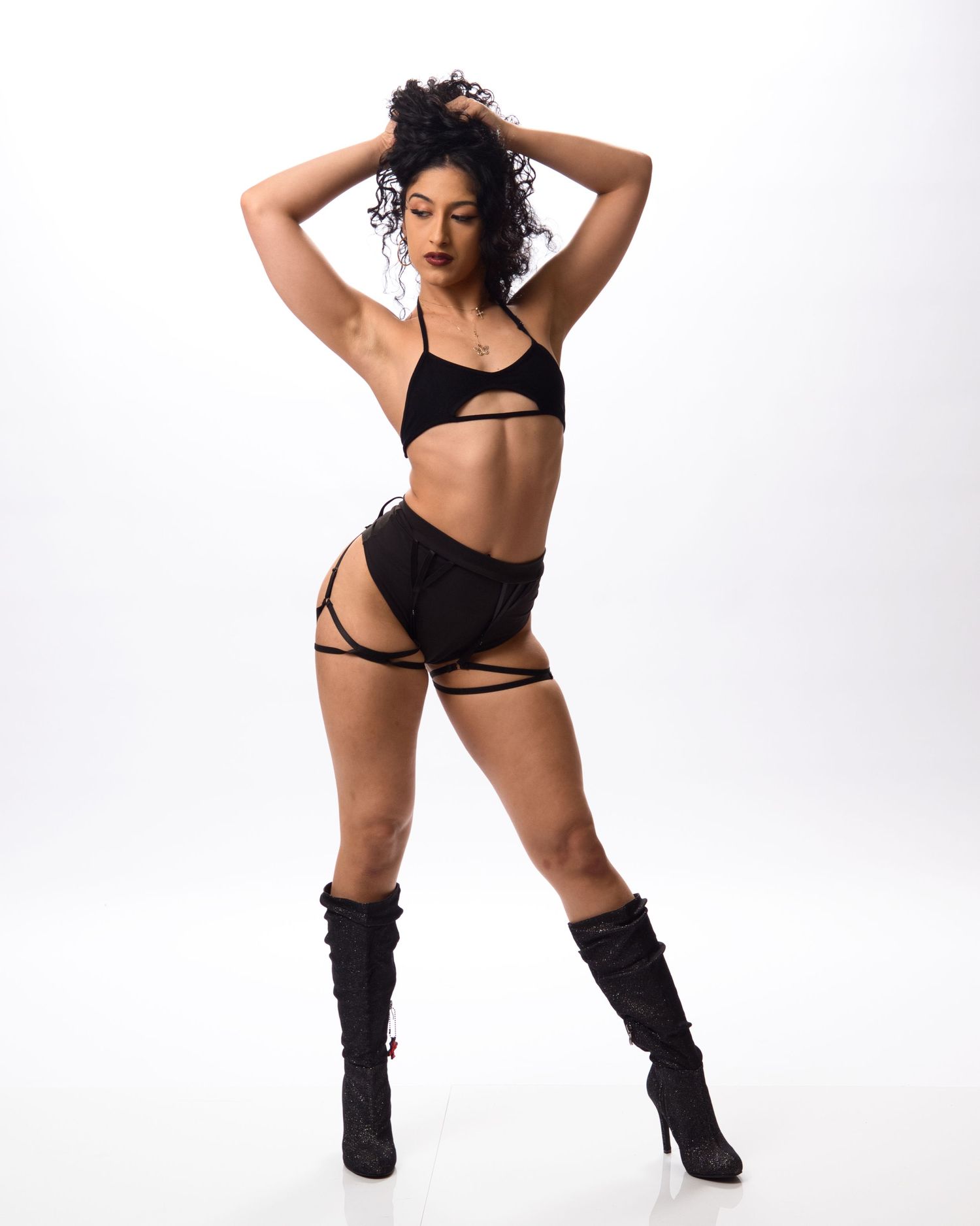 Athletic dancer striking dynamic pose in black activewear and boots against white background.