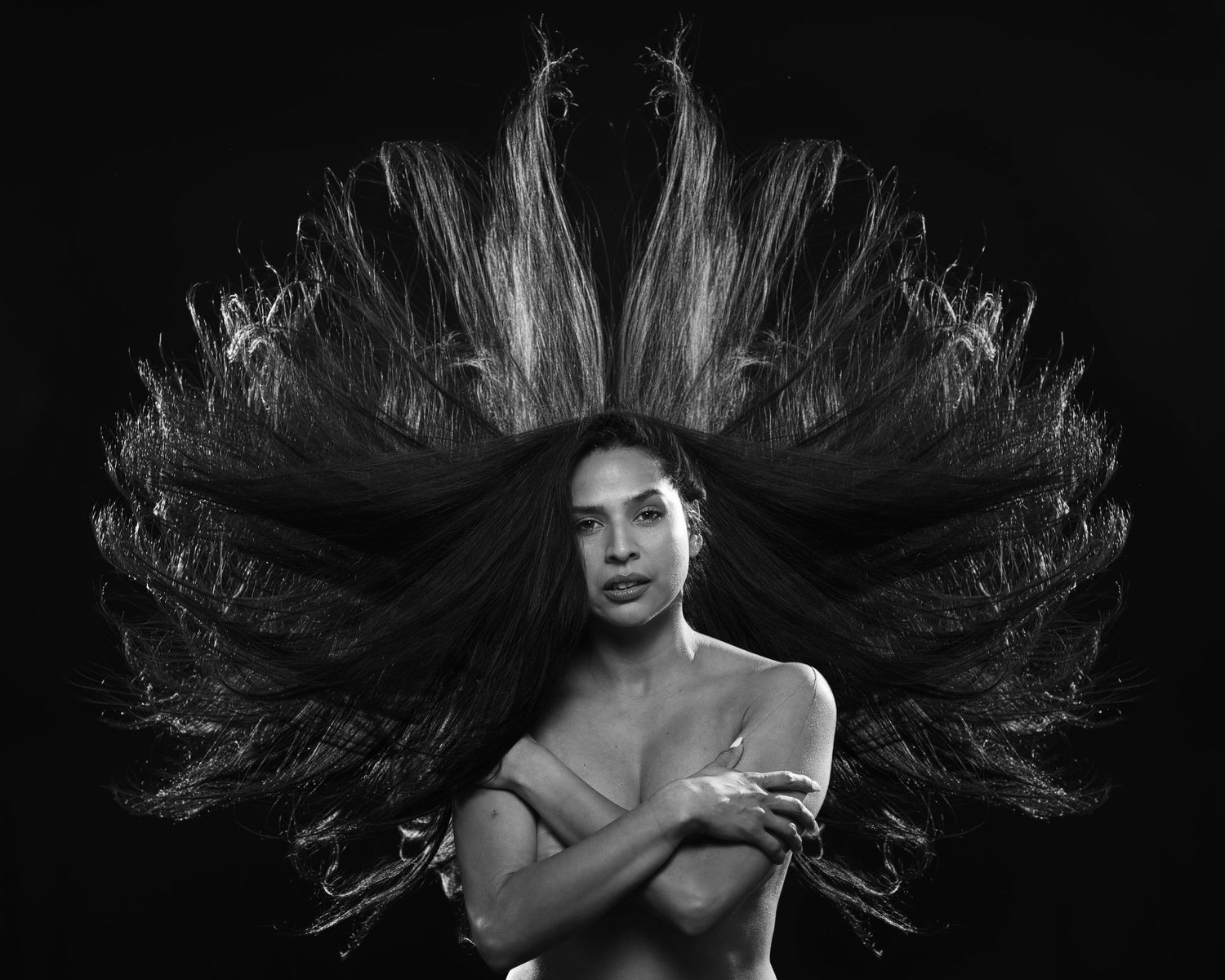 Black and white artistic portrait with dramatically fanned hair creating wing-like effect.