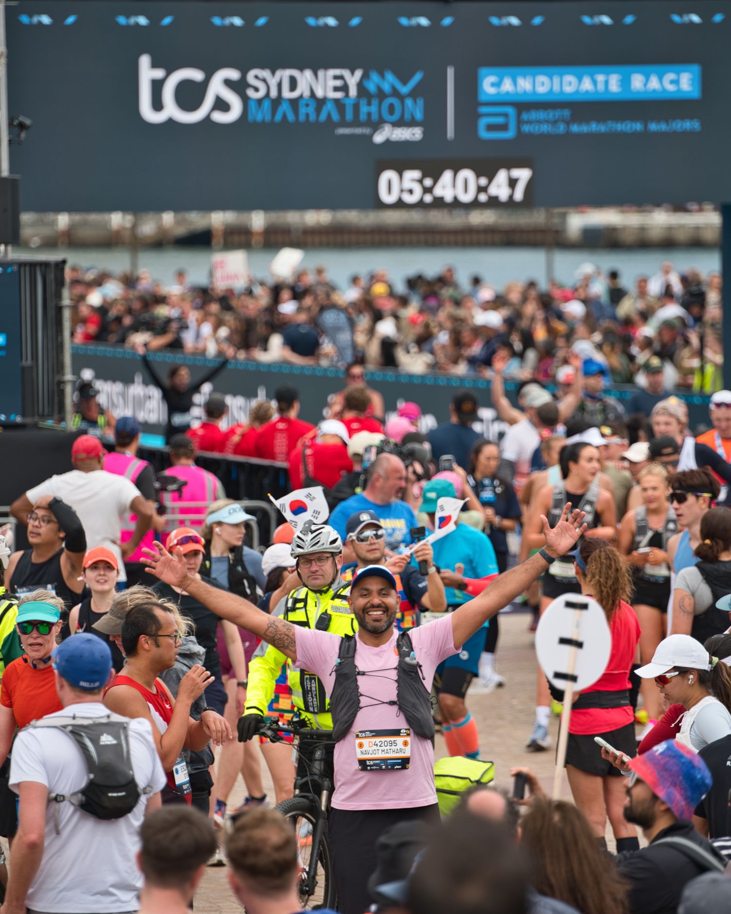 Large crowd of runners participating in Sydney Marathon with race timer display.