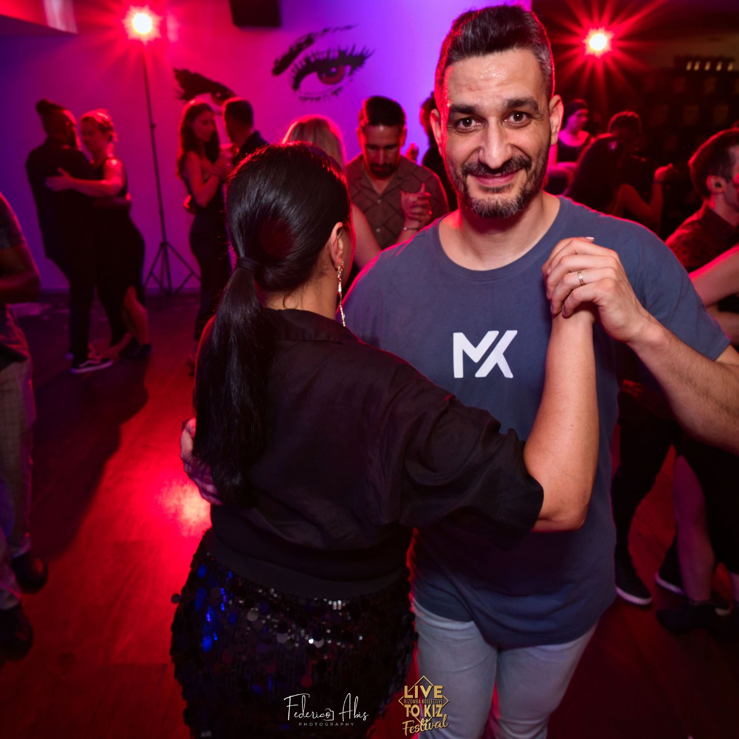 People dancing and socializing at nightclub with red ambient lighting.