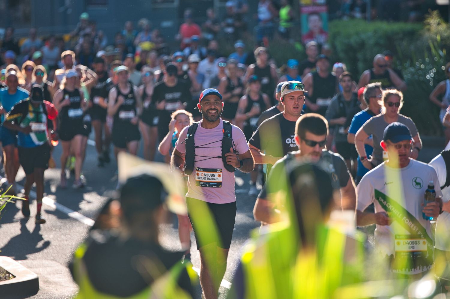Runners competing in marathon event with crowd and sunlight in background.