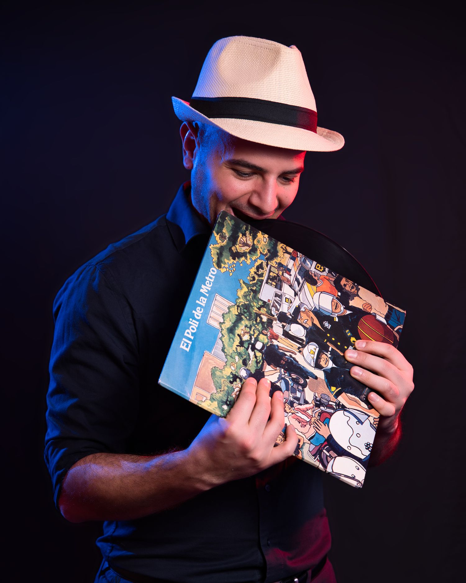 Person in fedora hat examining a vintage vinyl record album cover in dramatic lighting.
