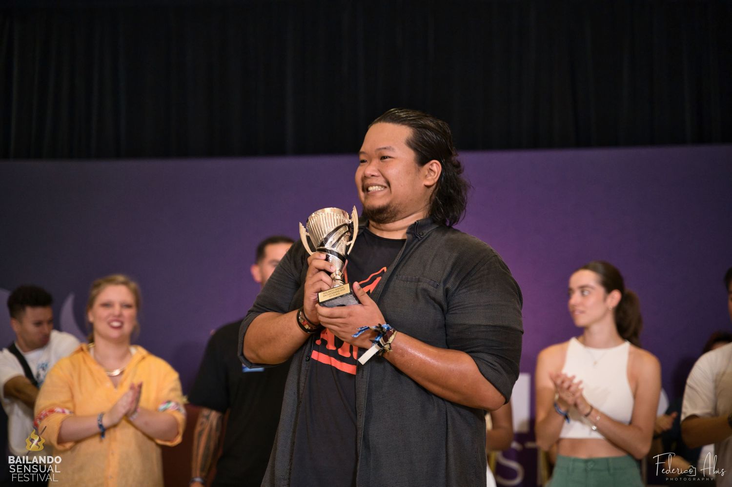 Performance on stage in front of an audience with people clapping in the background.