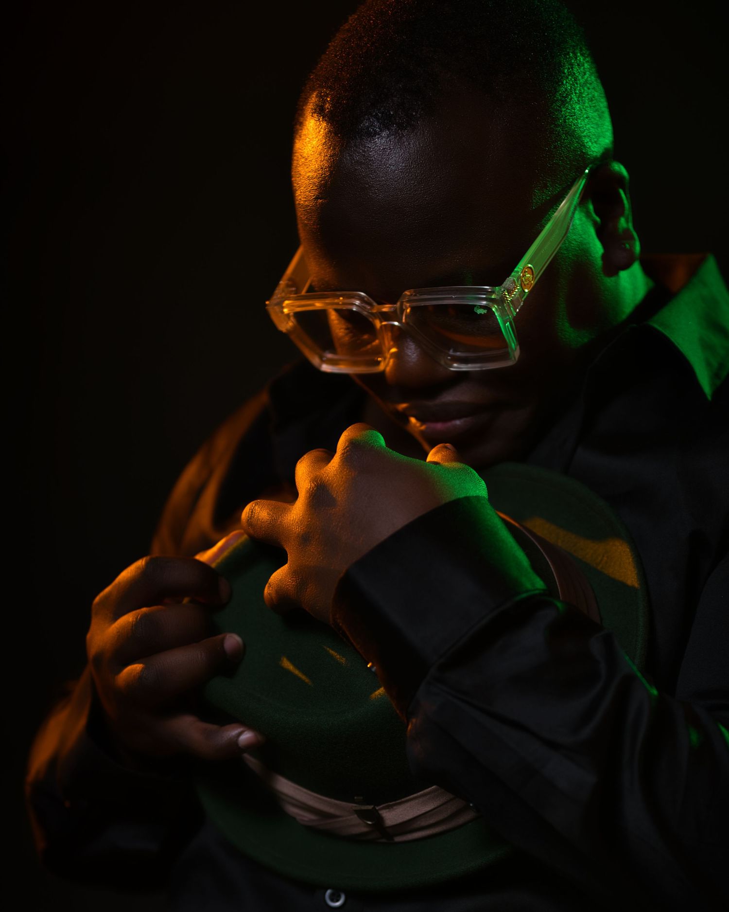 Dramatic lit portrait with orange and green lighting of person wearing glasses.