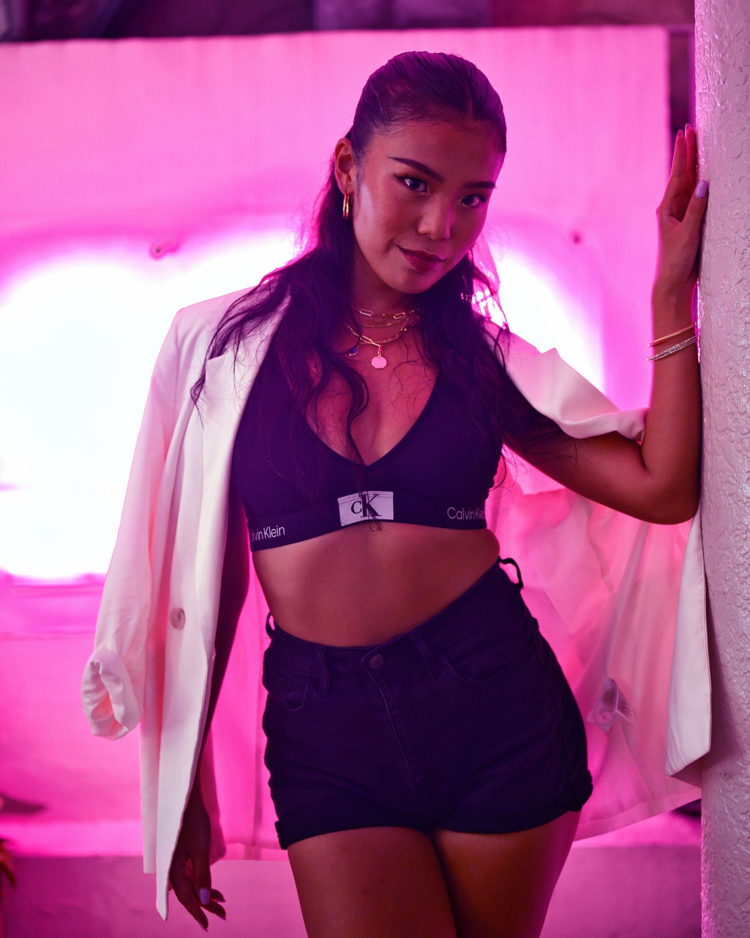 Athletic dancer in black activewear poses against pink illuminated background.