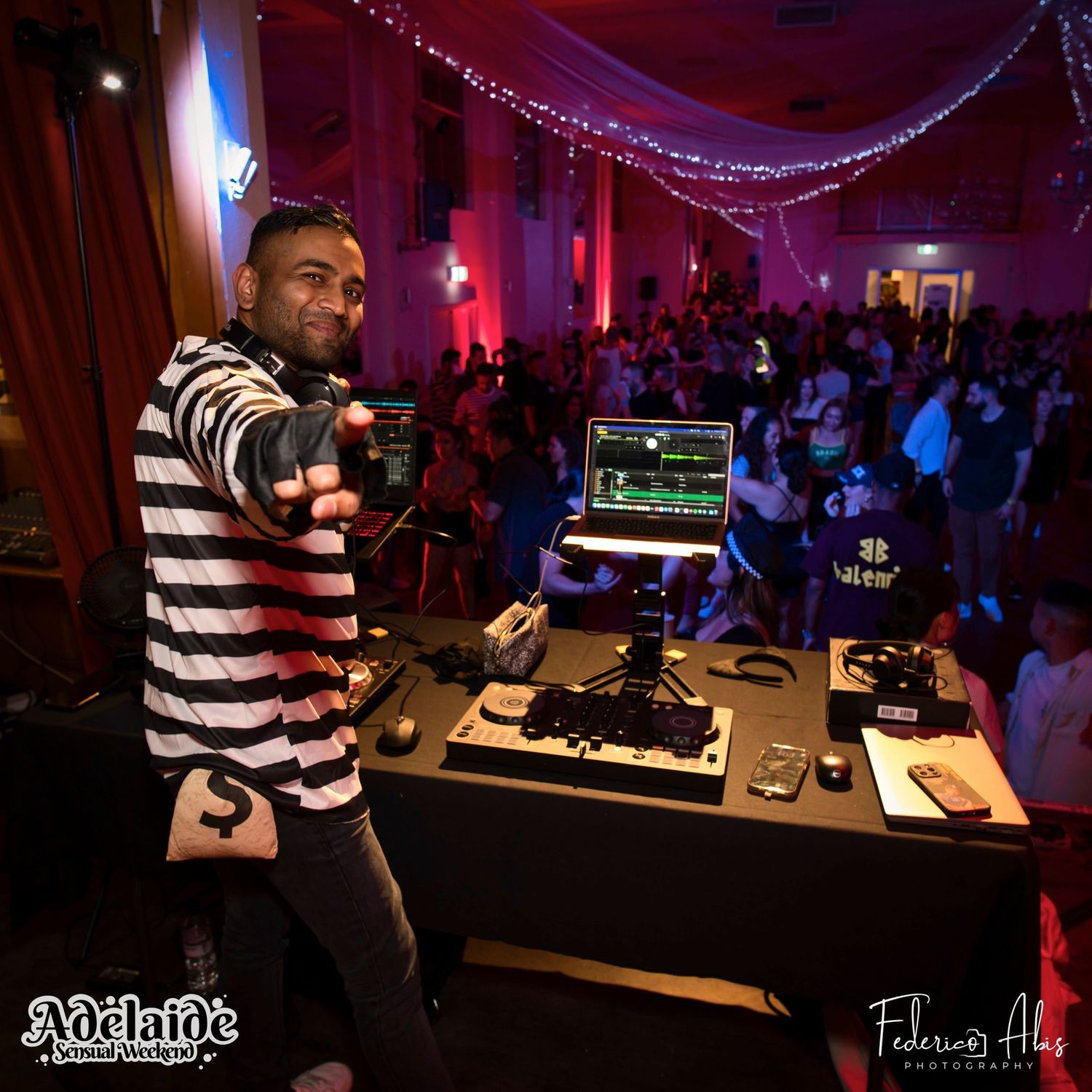 DJ performing at a nightclub event with professional equipment setup.
