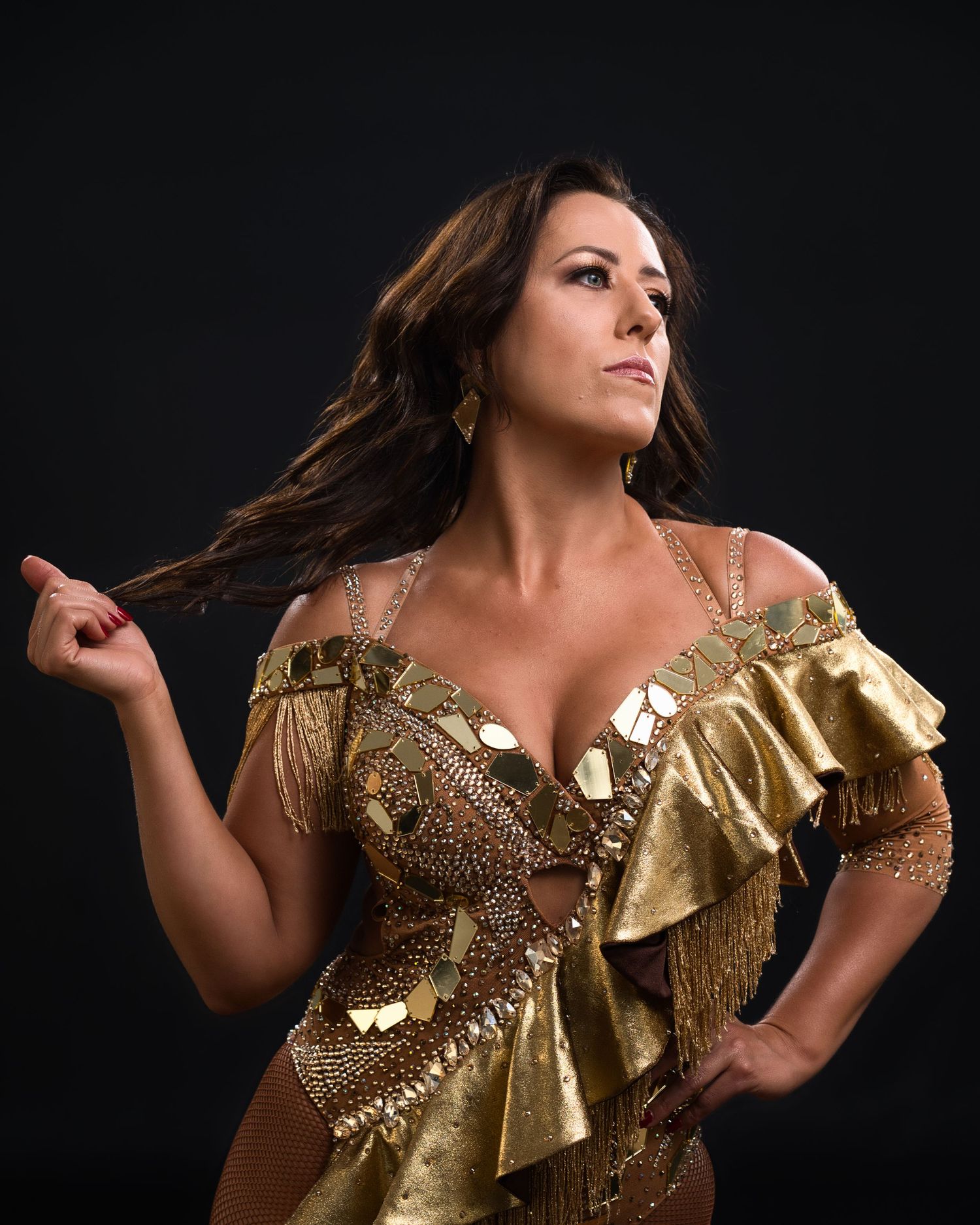 Performer in ornate gold costume with ruffles and sequins poses dramatically.