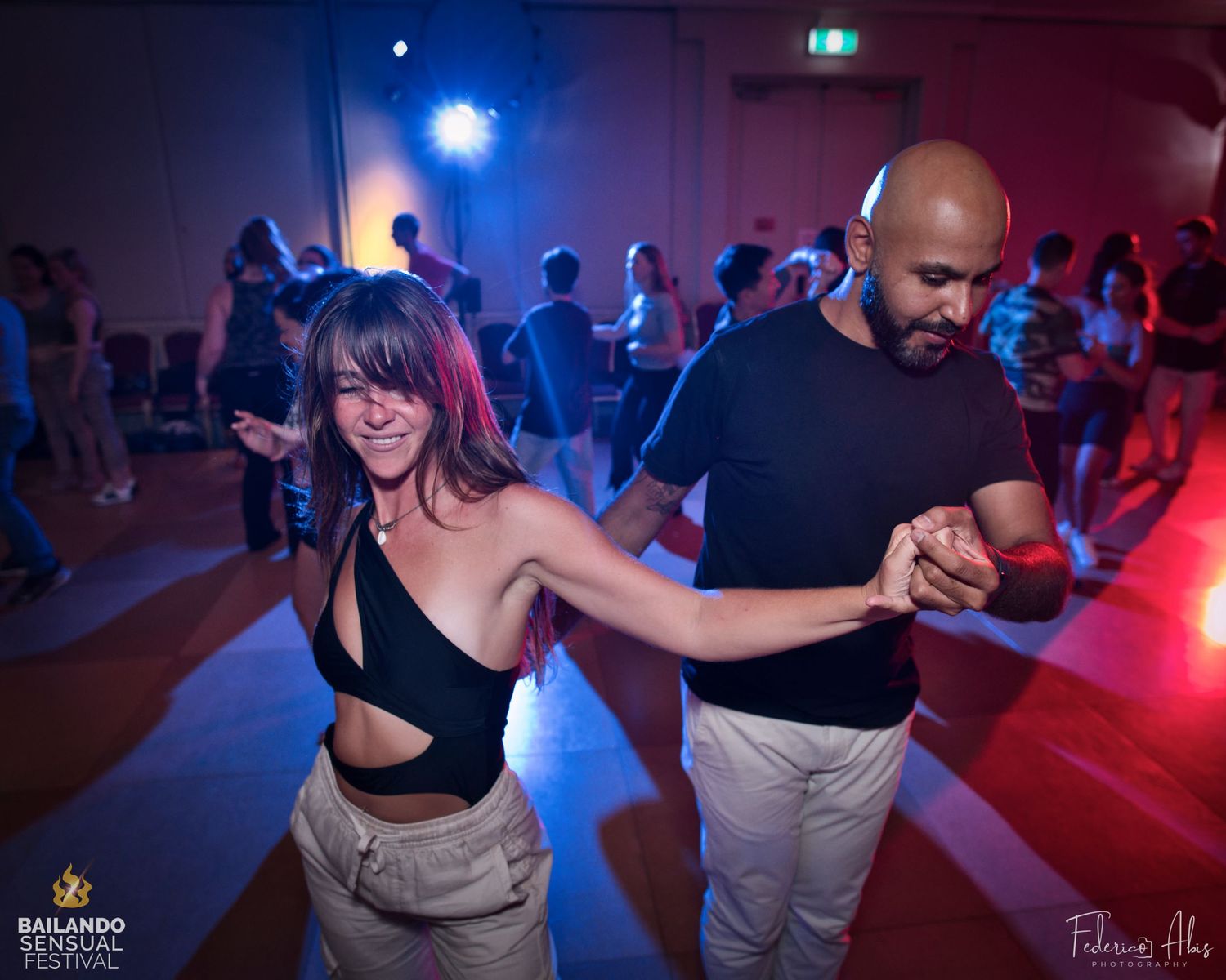 Dance partners performing a turn move on a dance floor with colorful lighting.