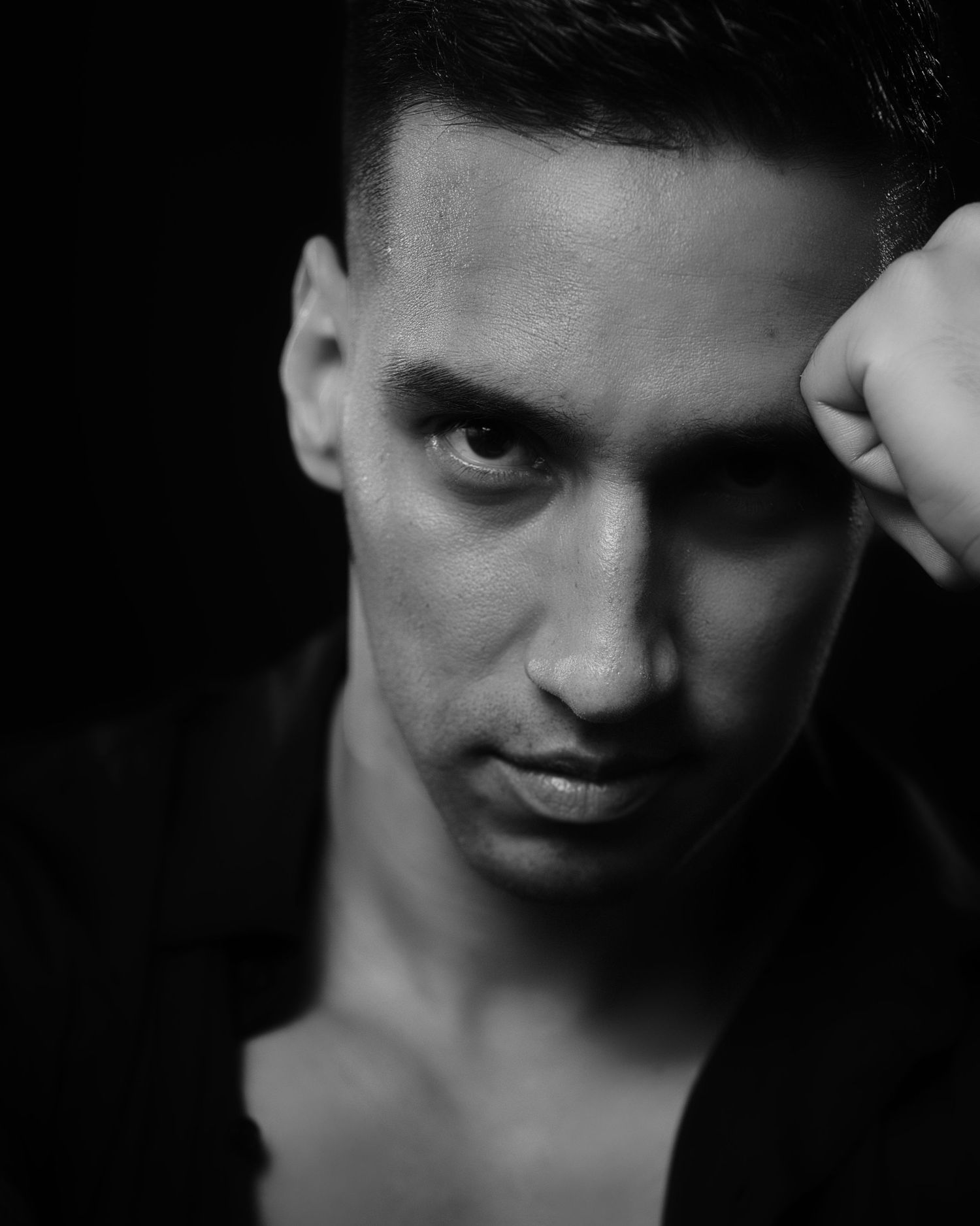 Black and white portrait photo showing dramatic side lighting on face against dark background.
