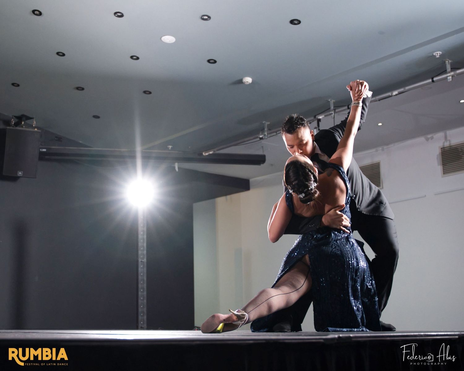 Dancers execute dramatic lift move during performance on dimly lit stage.