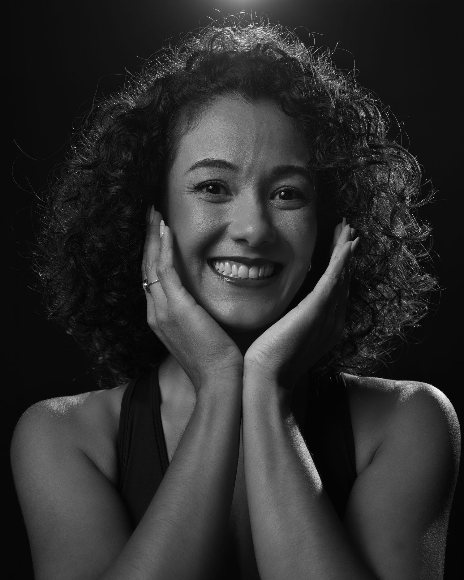 Expressive black and white headshot of performer with natural curls and genuine smile.