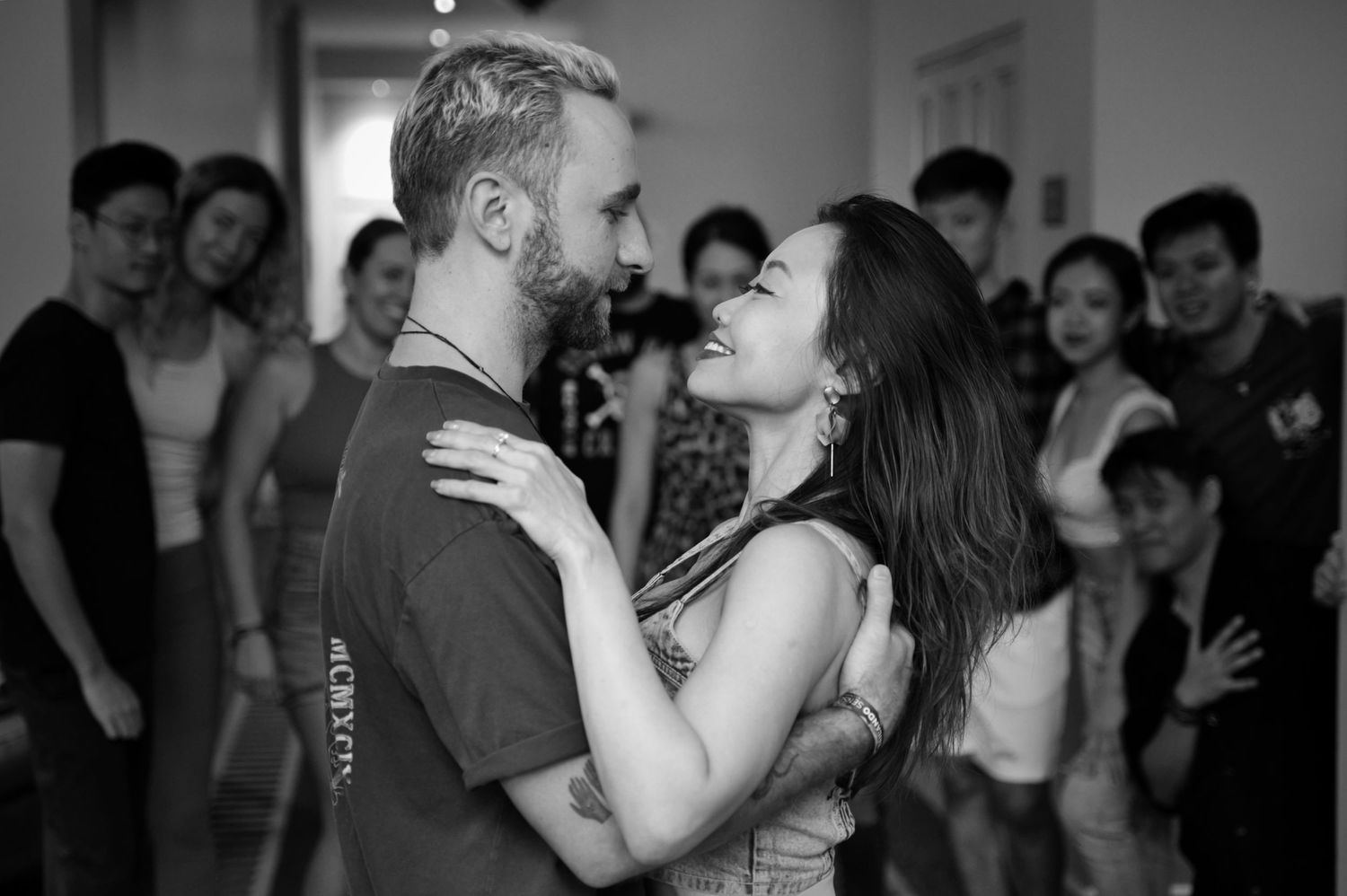 Intimate dance moment captured in black and white with crowd in background.