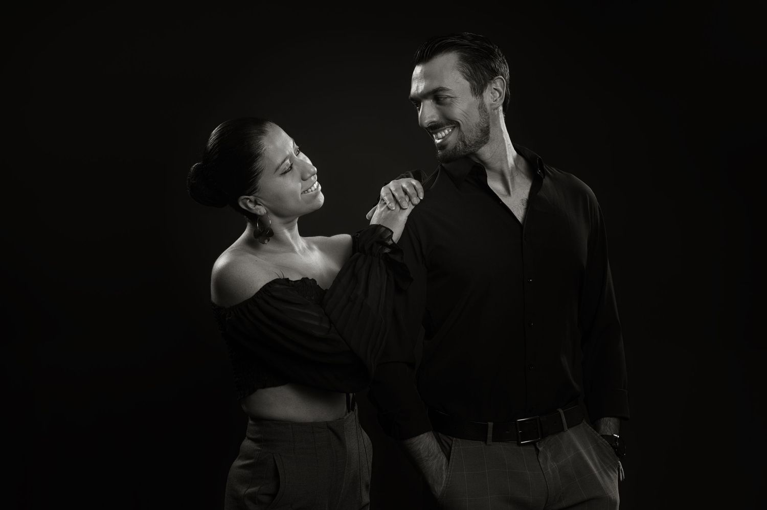 Couple sharing joyful moment while dancing together in black and white portrait.