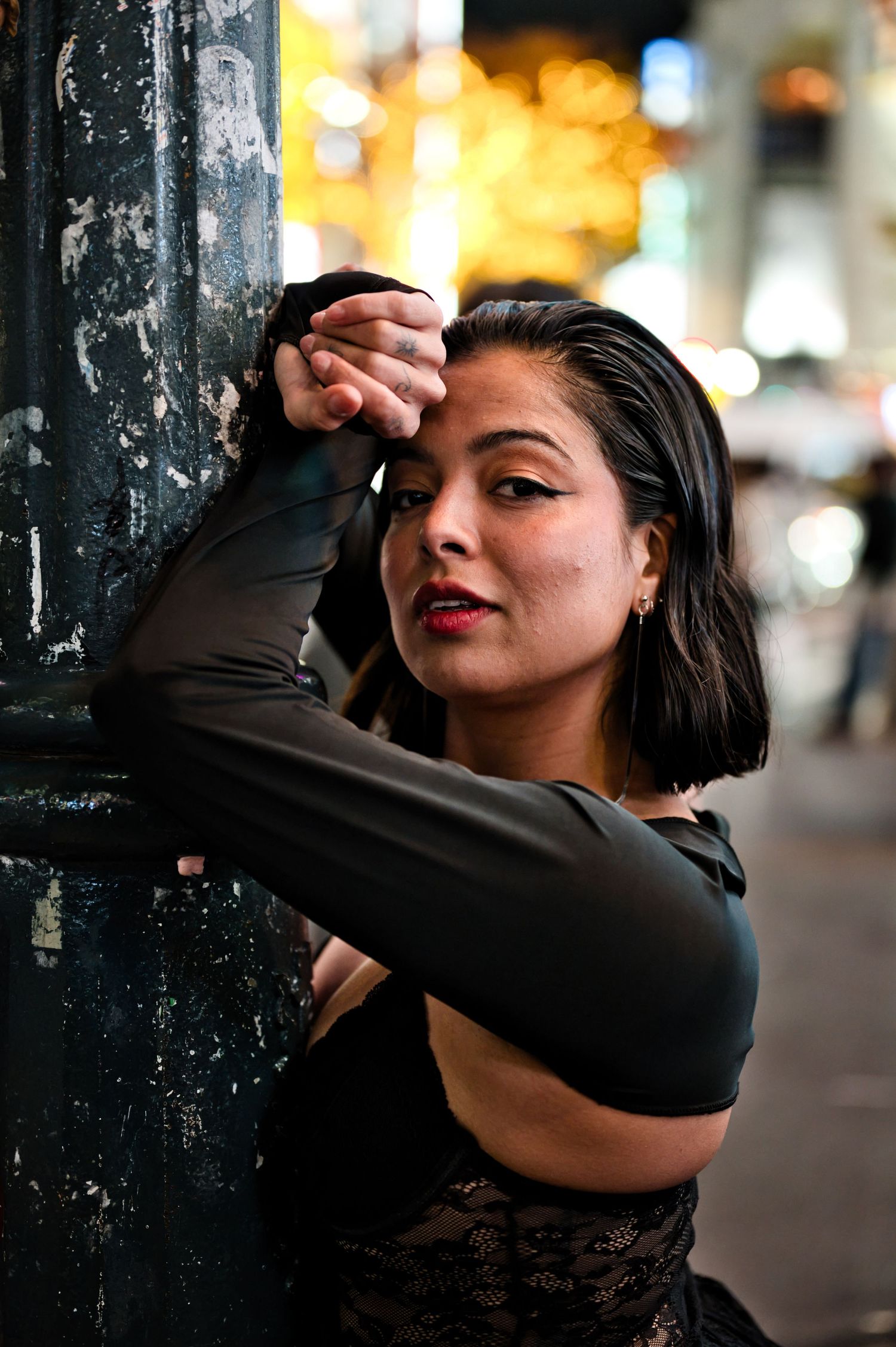 A dancer in black poses dramatically against an urban backdrop with city lights.