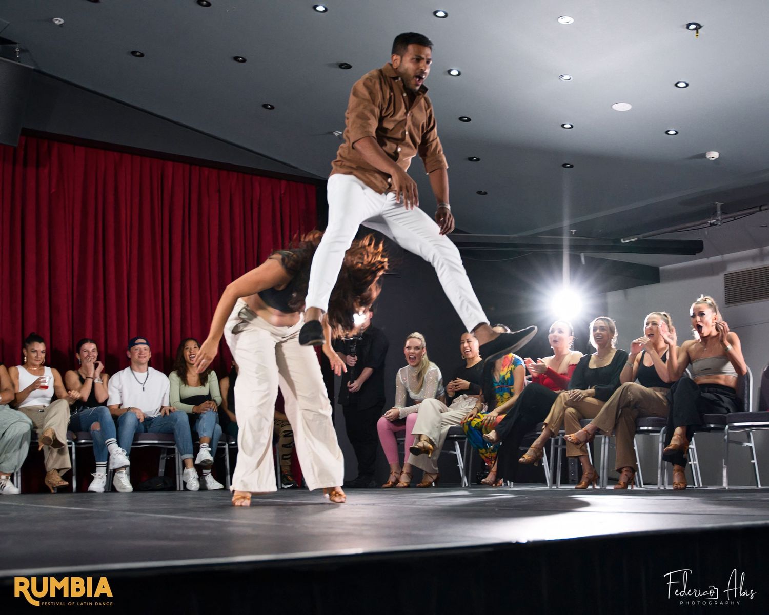Acrobatic dance performance featuring a dramatic lift on stage with audience members watching.