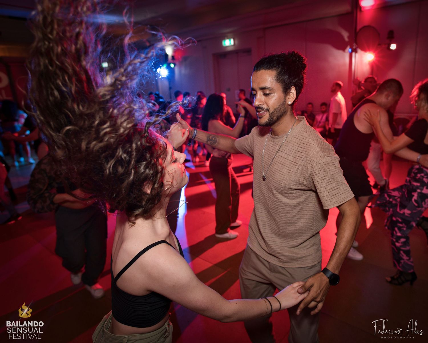 Dance partners in motion on a dimly lit dance floor with red lighting.