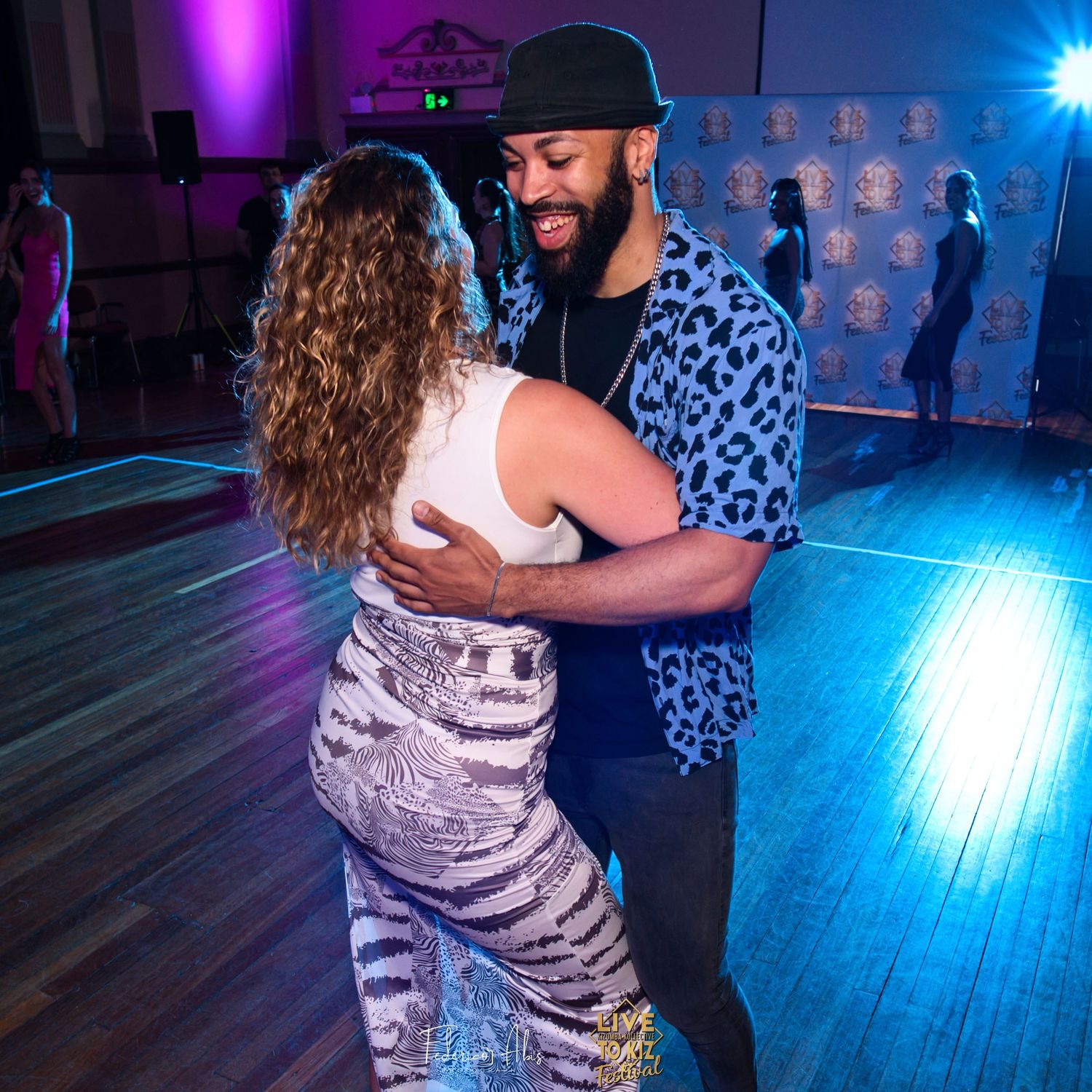 Couple dancing together at a vibrant nightclub with blue and purple lighting on the dance floor.
