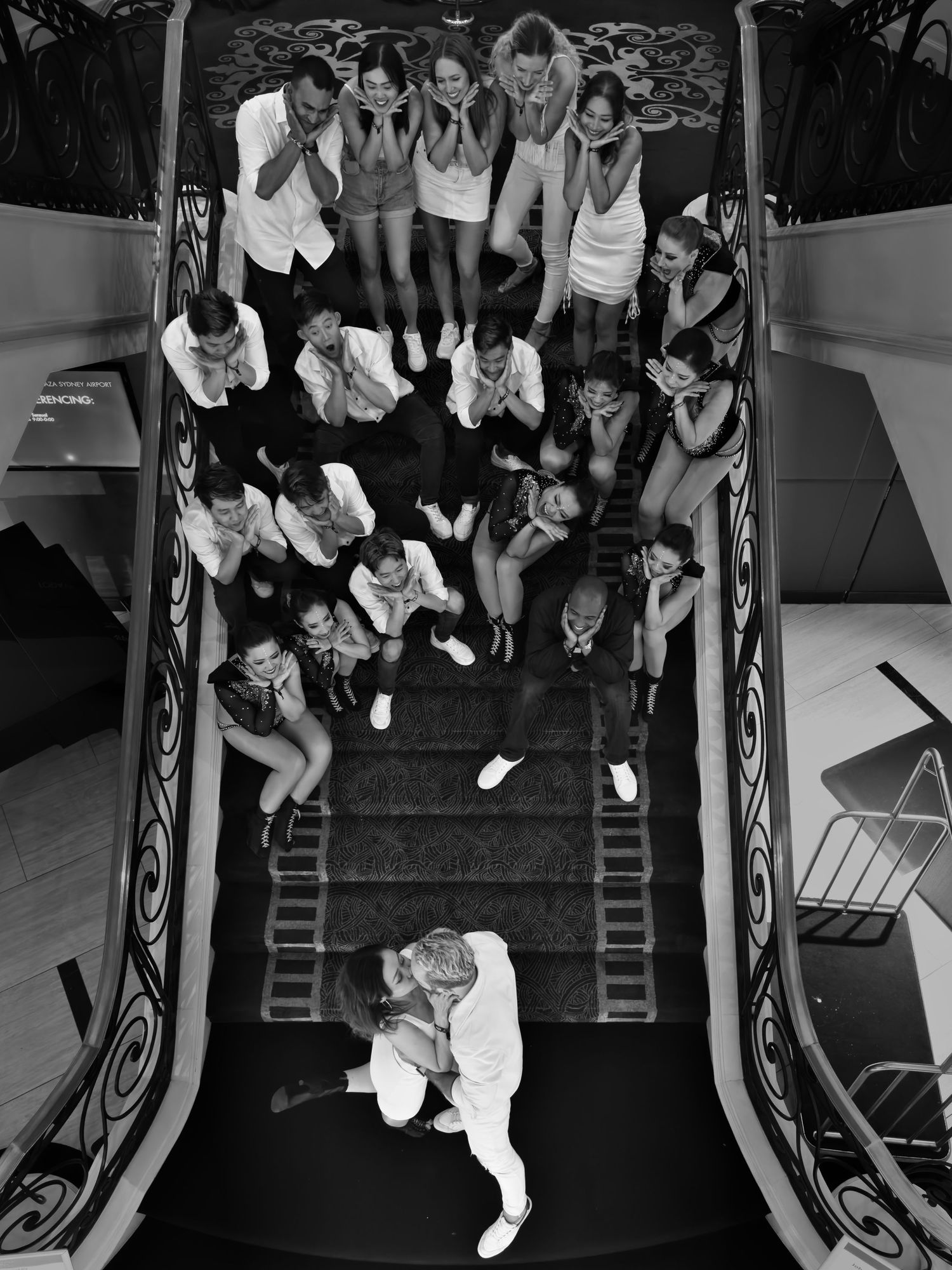Overhead view of group celebration on elegant spiral staircase in black and white.