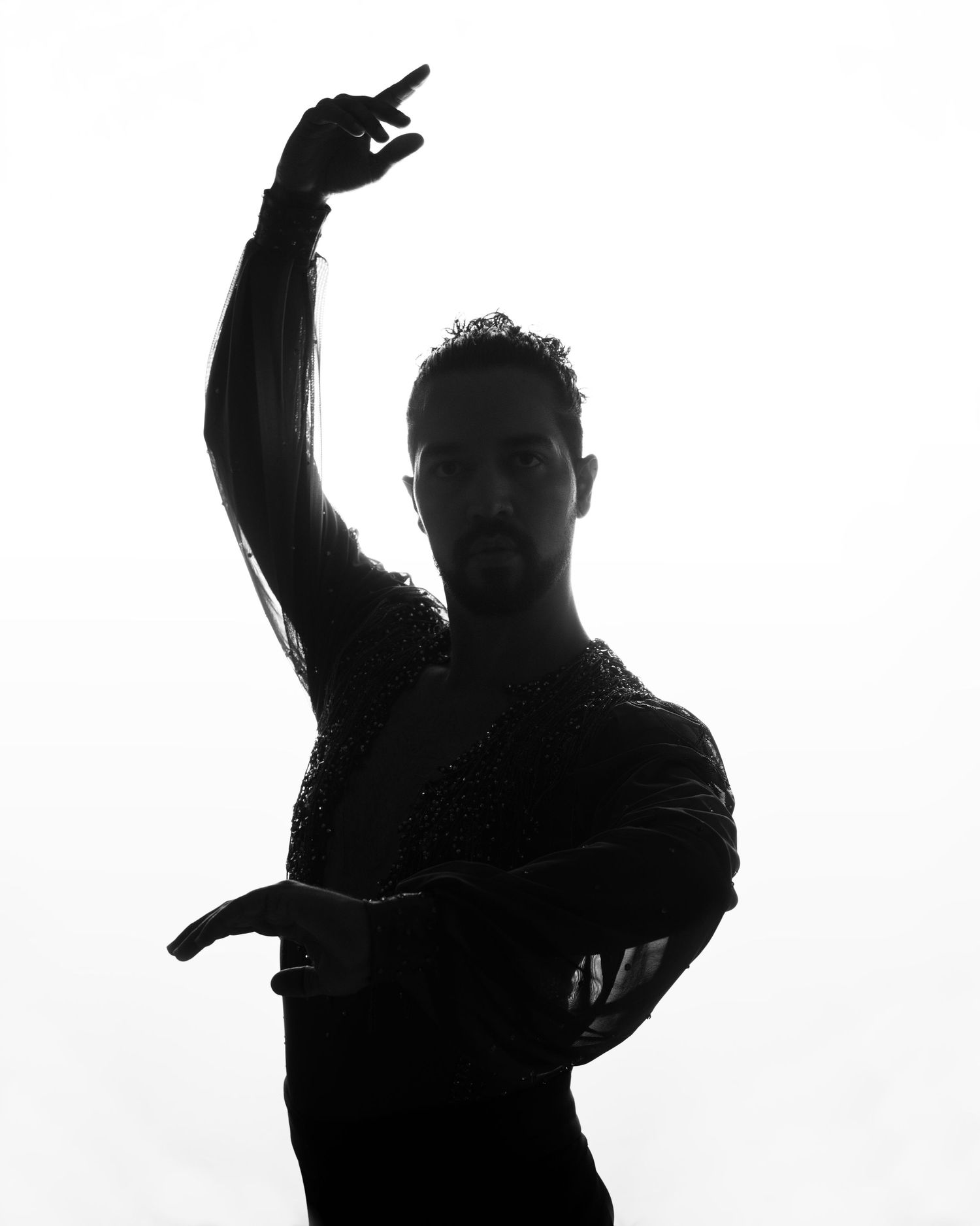 Artistic silhouette of a dancer with raised arm against white background.