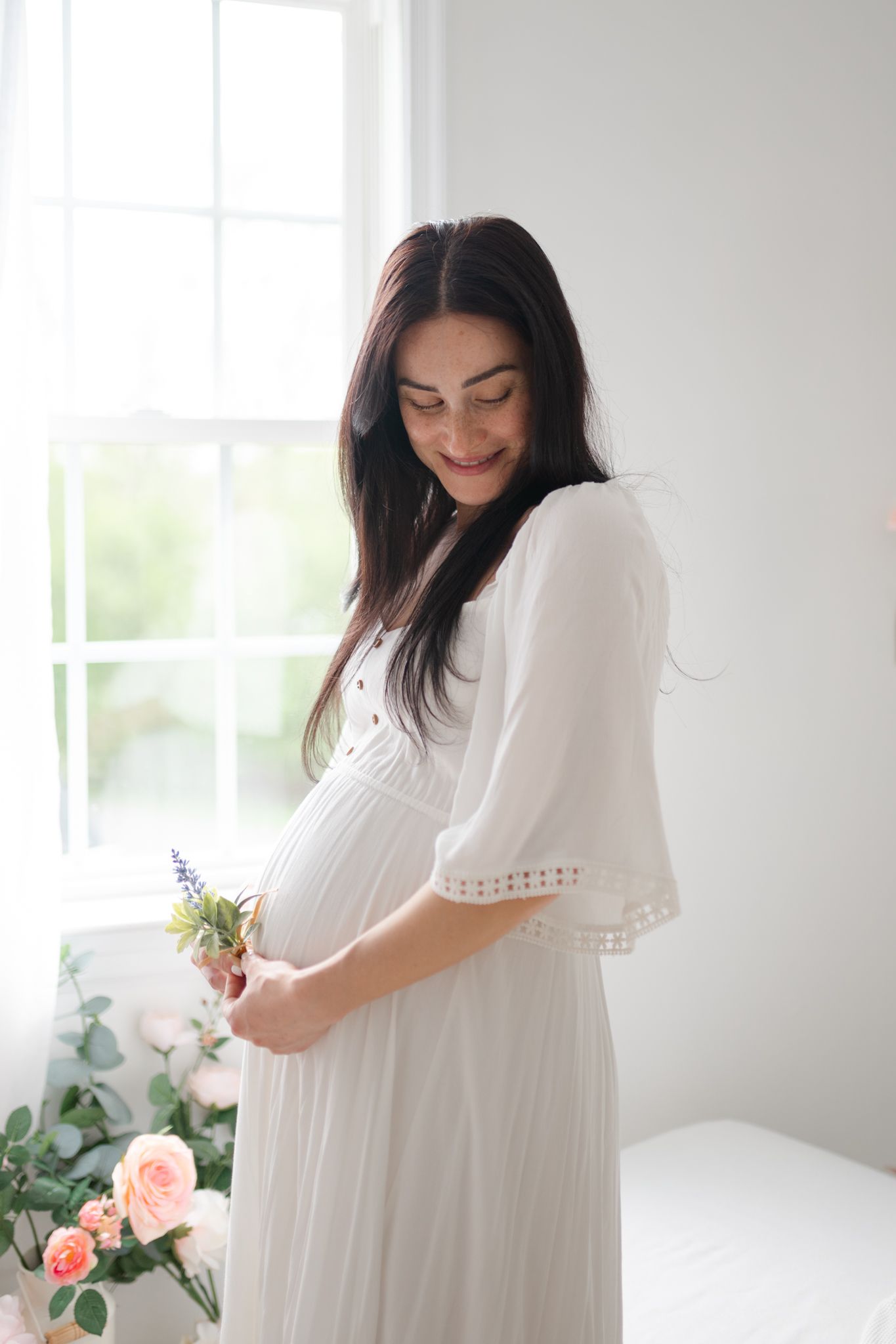 pregnant mom in white dress in front of window by Richmond newborn photographer