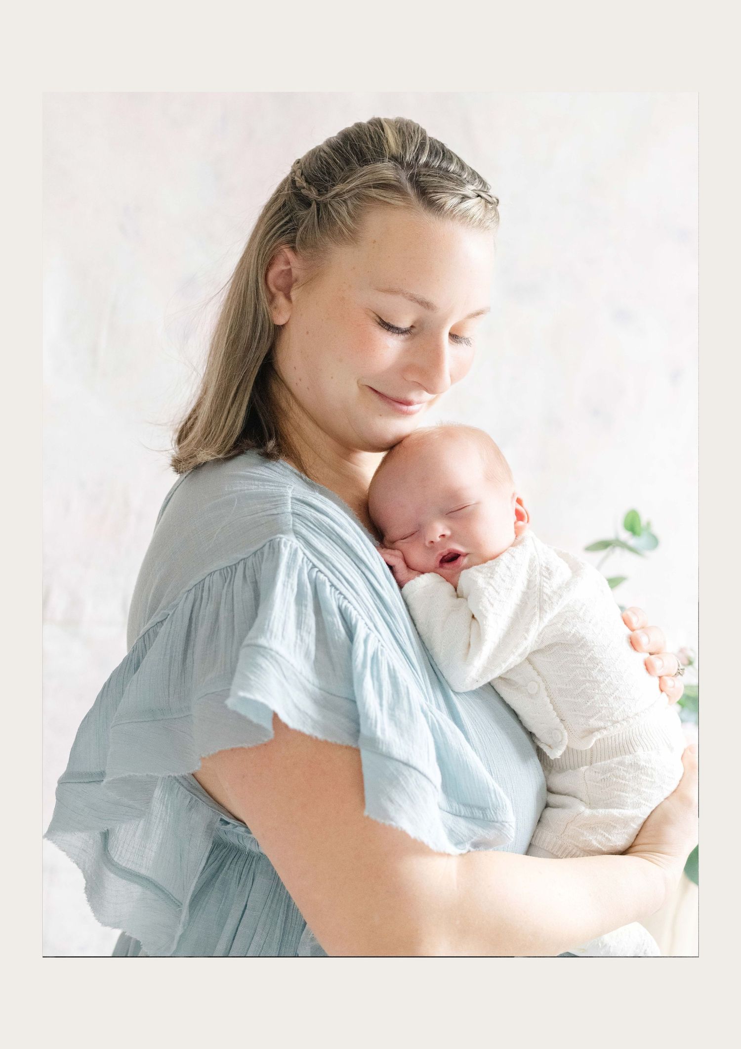 Mother holding her newborn baby in soft natural light during a motherhood photography session in Midlothian Virginia