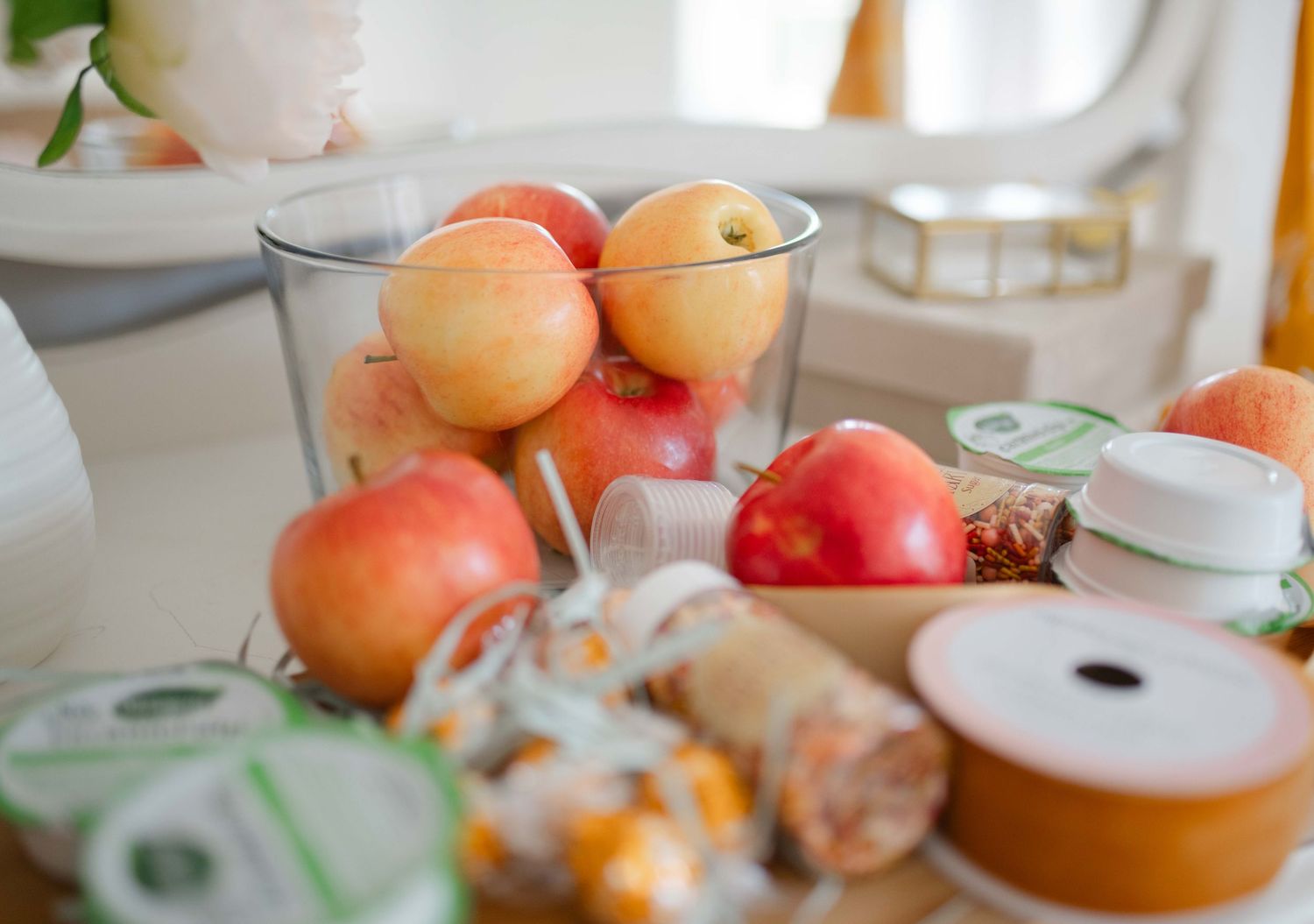 Fresh oranges and apples arranged on a white surface with a decorative wooden bowl in soft natural lighting.