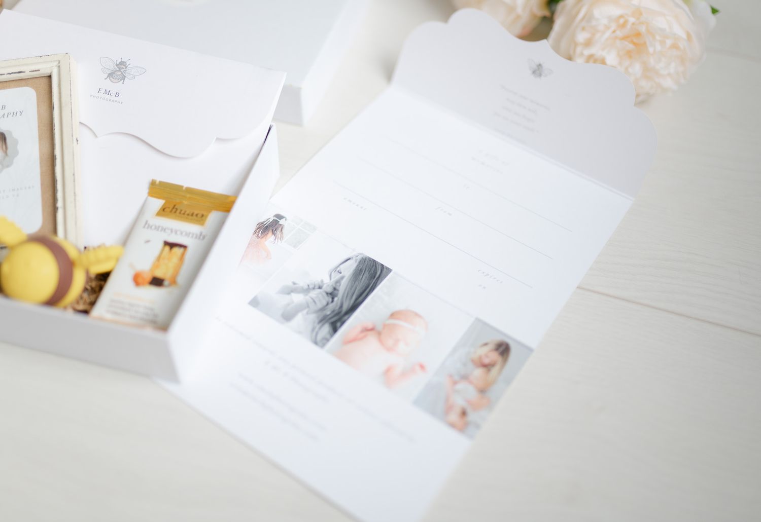 Flat lay of pastel colored photographs and artwork scattered on a white surface with soft natural lighting.