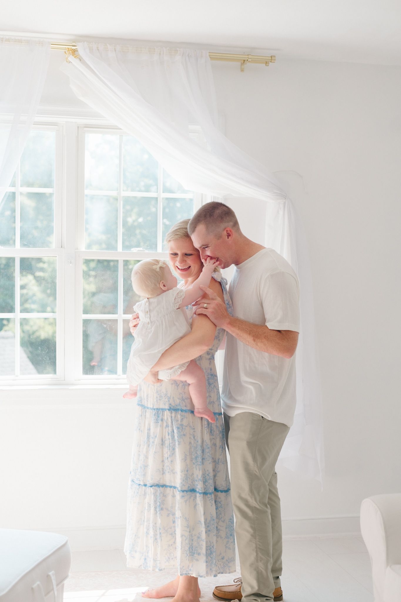 Family sharing intimate moment in bright white room with flowing curtains.