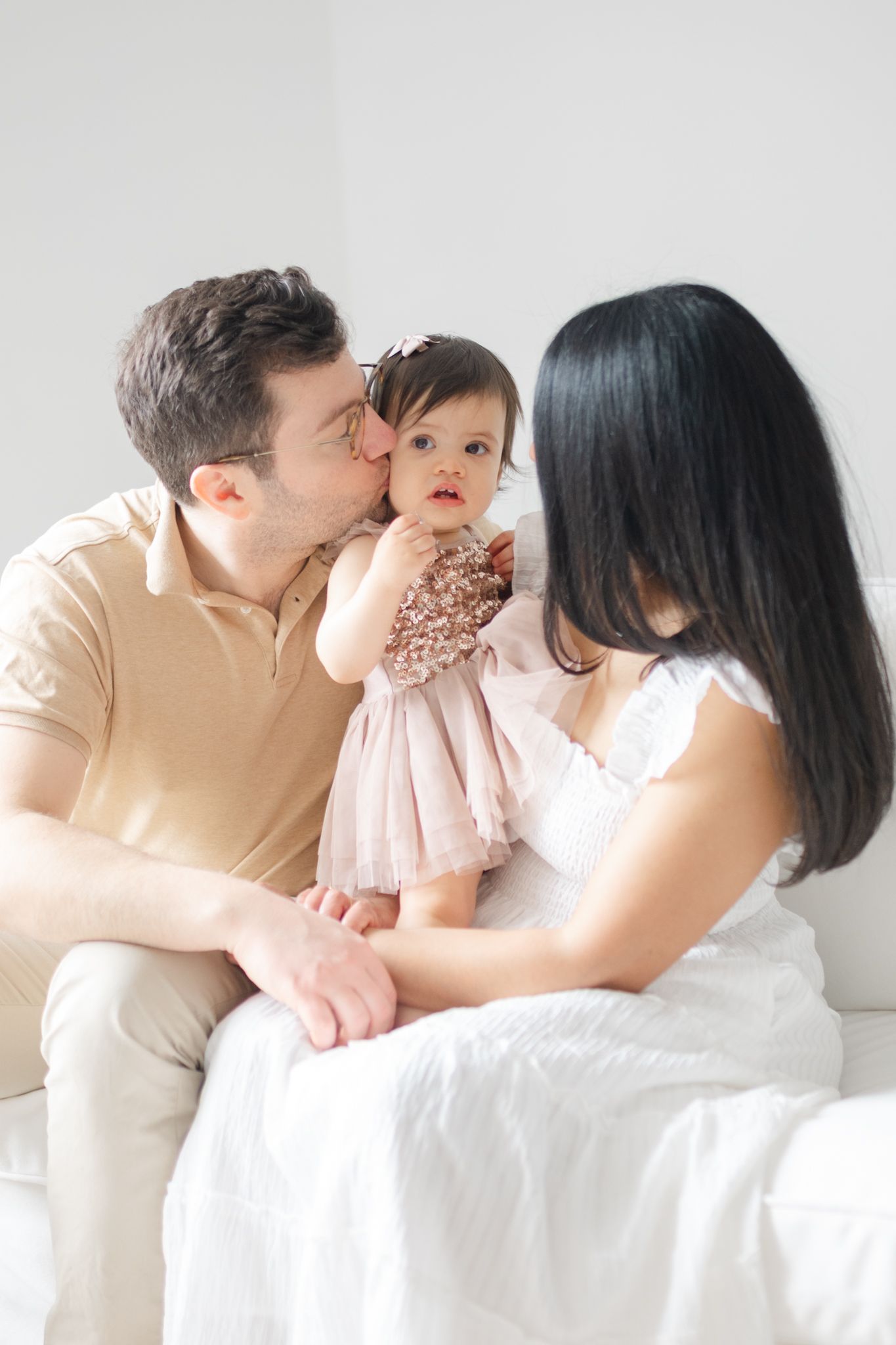 Family sharing an intimate moment together on white couch.