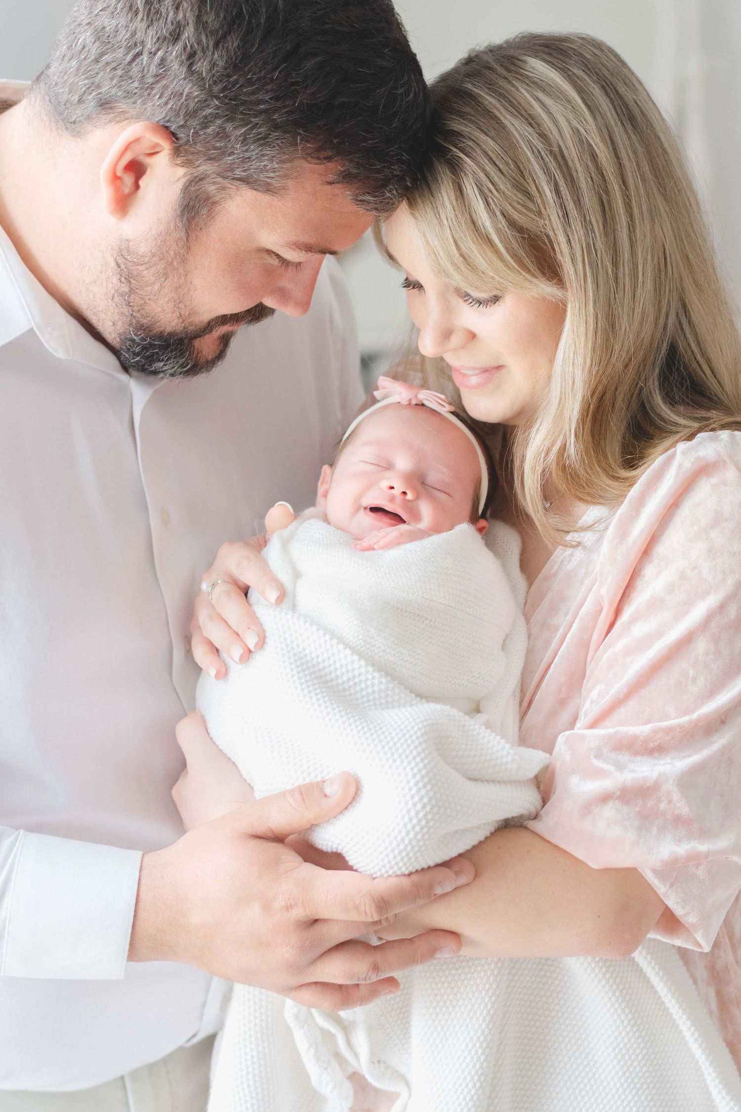 Happy swaddled newborn in parents arm during a newborn session in Richmond Virginia .