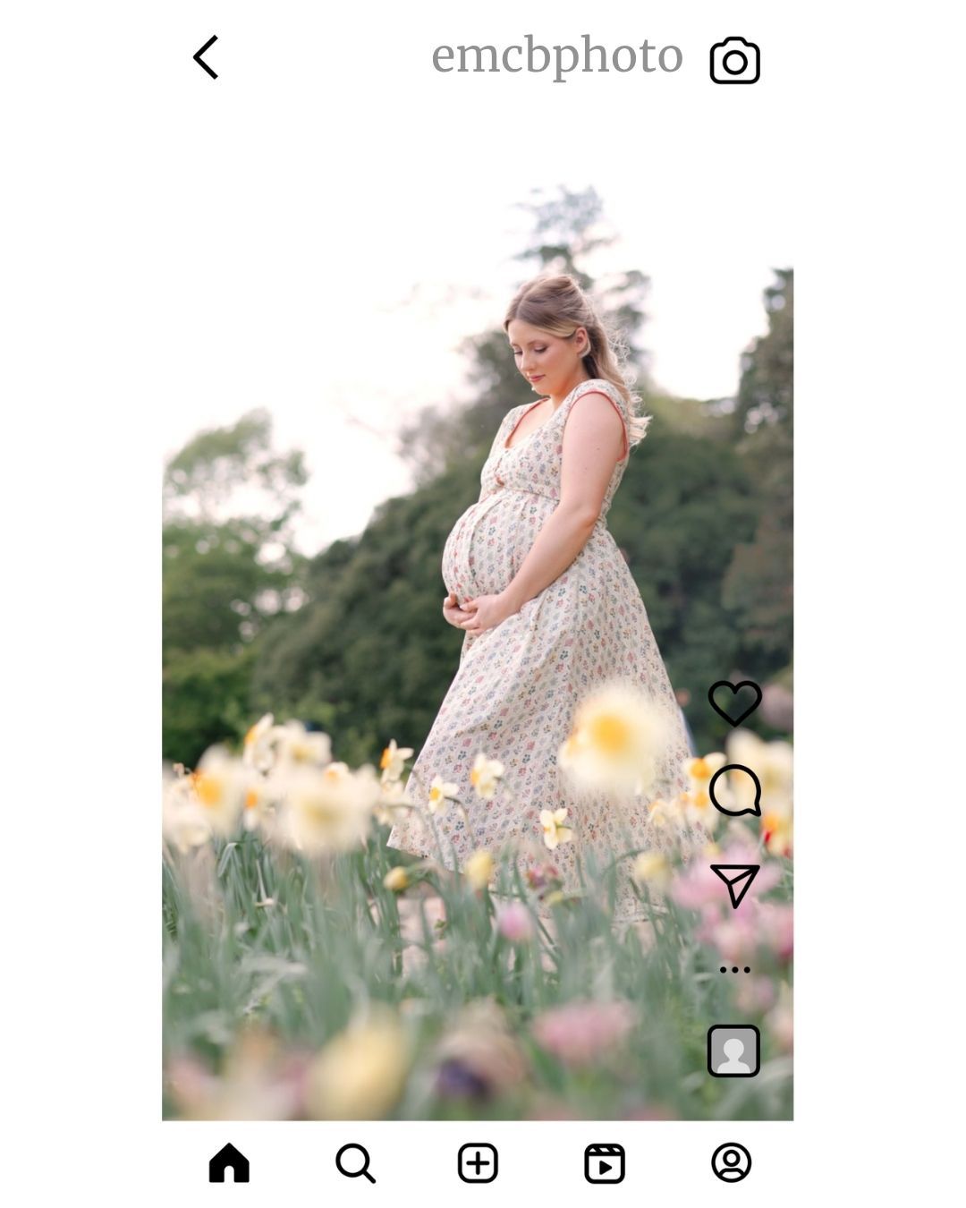 Pregnant woman in floral dress standing in blooming garden field during maternity photo session outdoors.