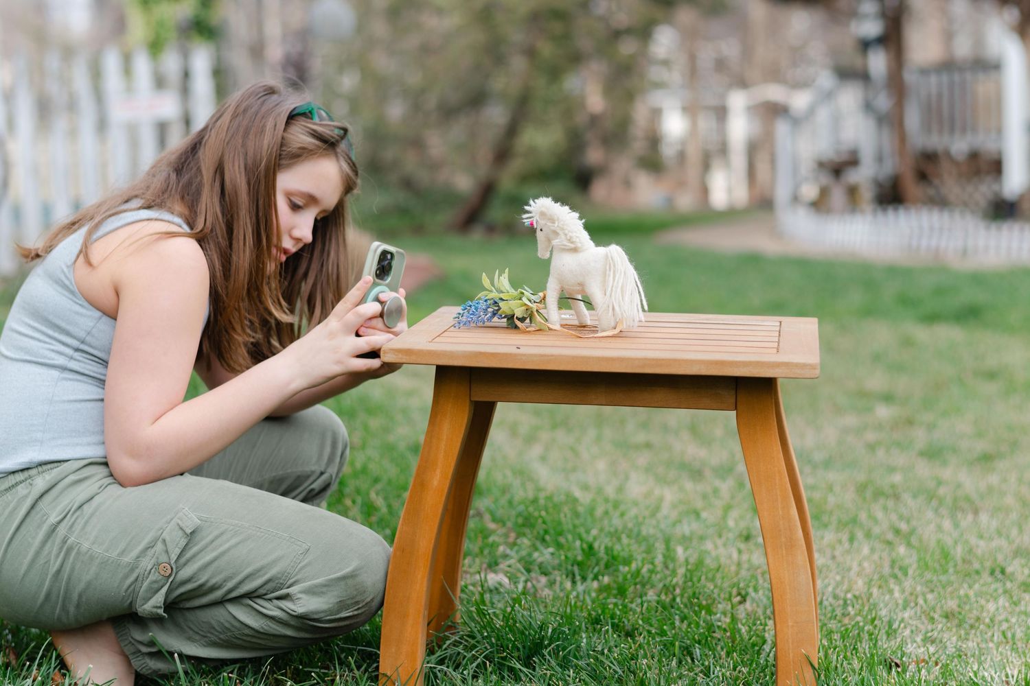 Person sitting on grass with wooden table enjoying outdoor picnic with coffee and snacks.