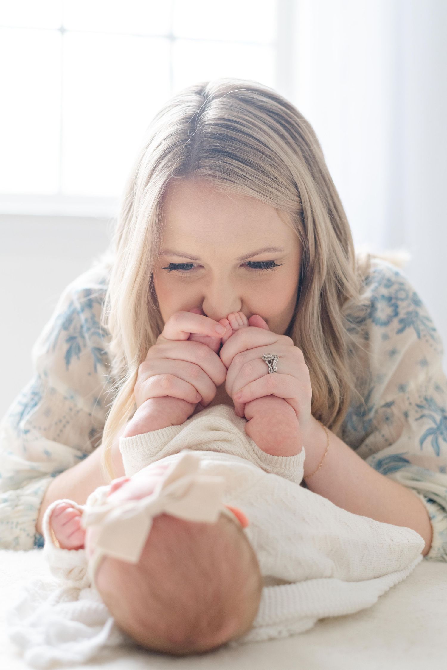 Mother cuddling newborn on white bedding, soft natural light newborn session in Richmond Virginia