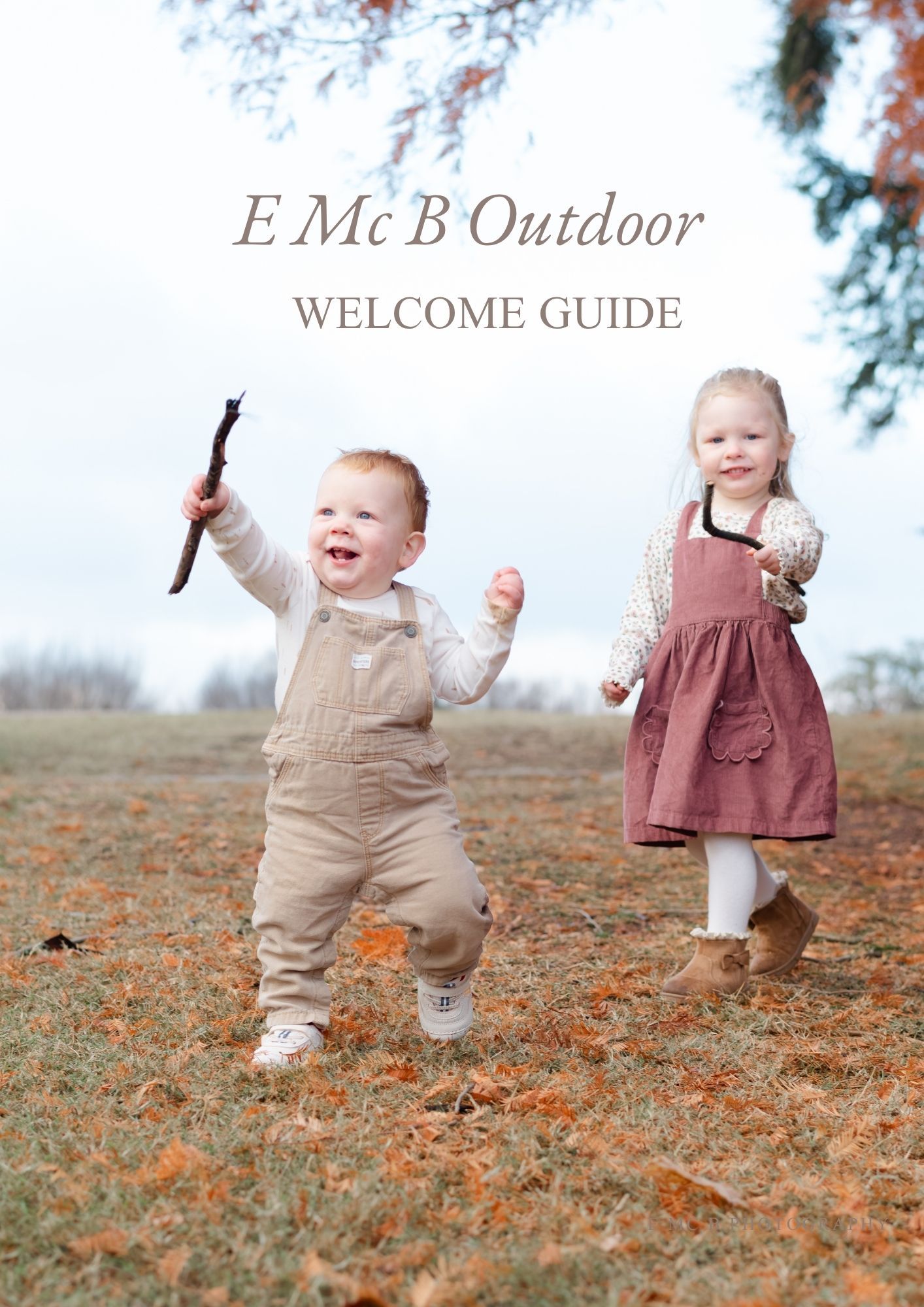 Two toddlers playing outdoors in a field, boy in overalls holding a stick and girl in pink dress, E Mc B Outdoor Welcome Guide.