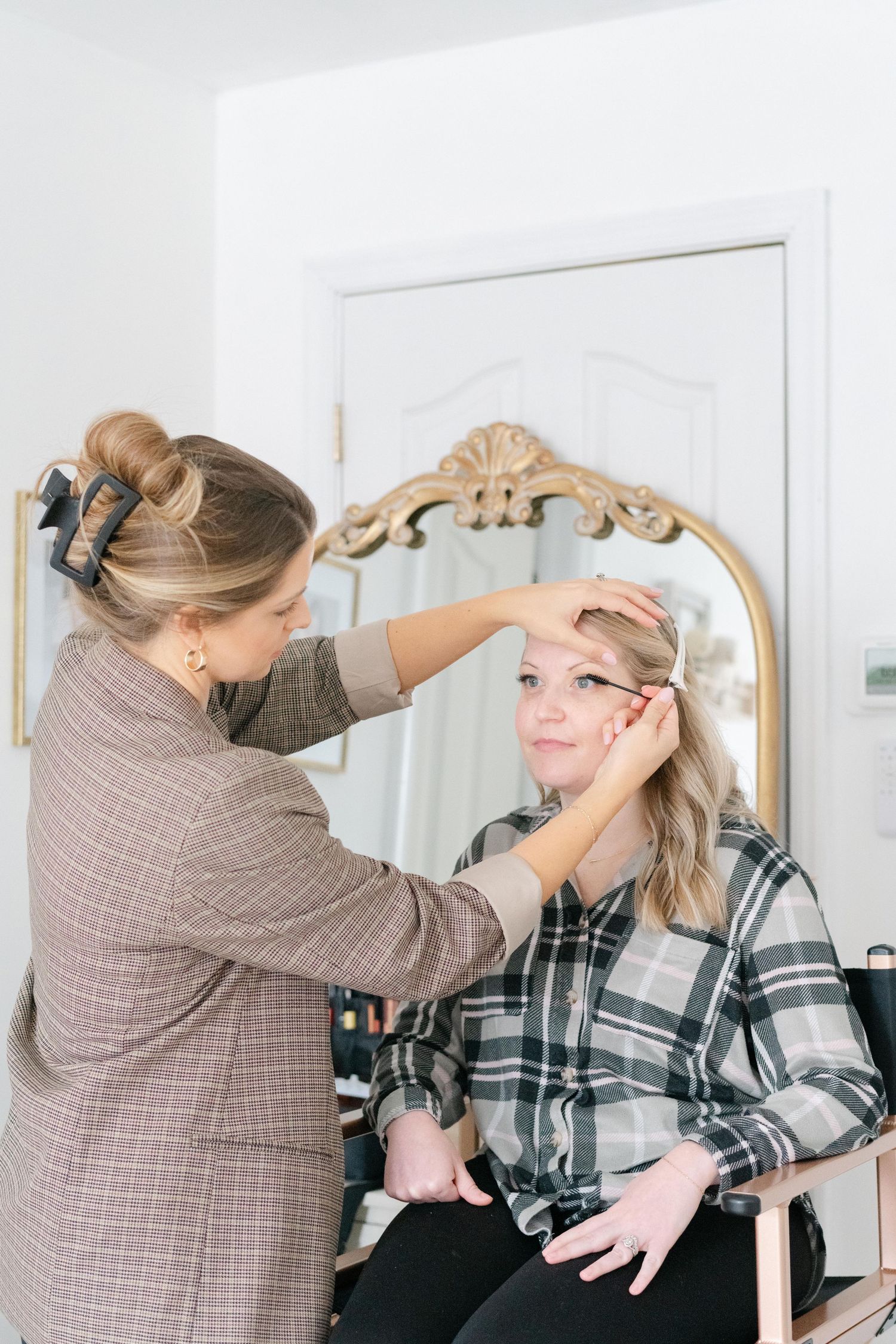 A Richmond stylist applies makeup and does hair styling in a bright white room with mirror reflections.