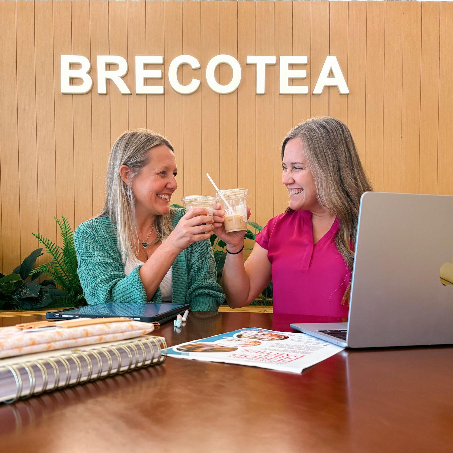 Two students study together at a table while sharing notes and having a discussion.