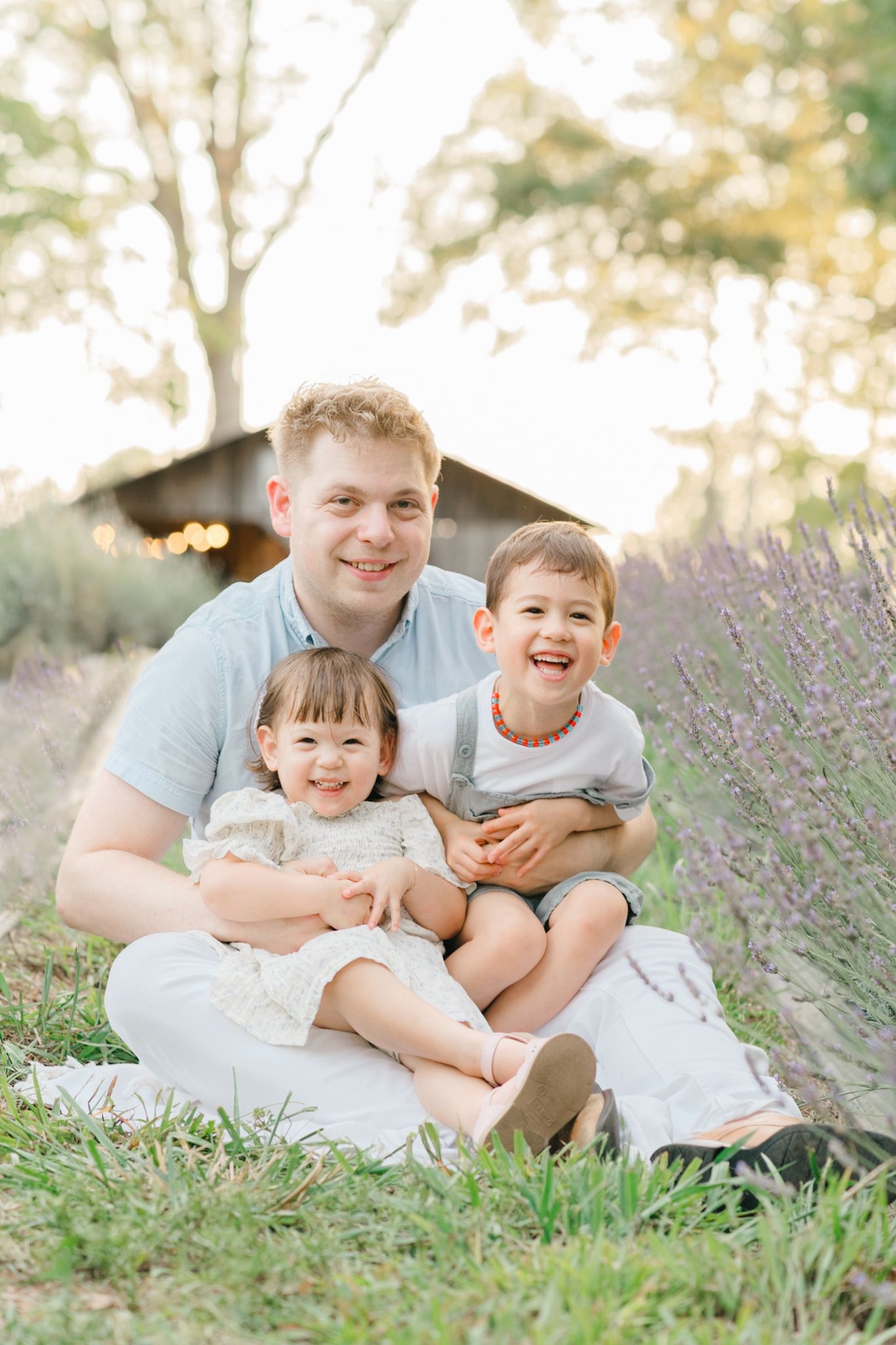 Family sitting together in a lavender field during golden hour sunset.
