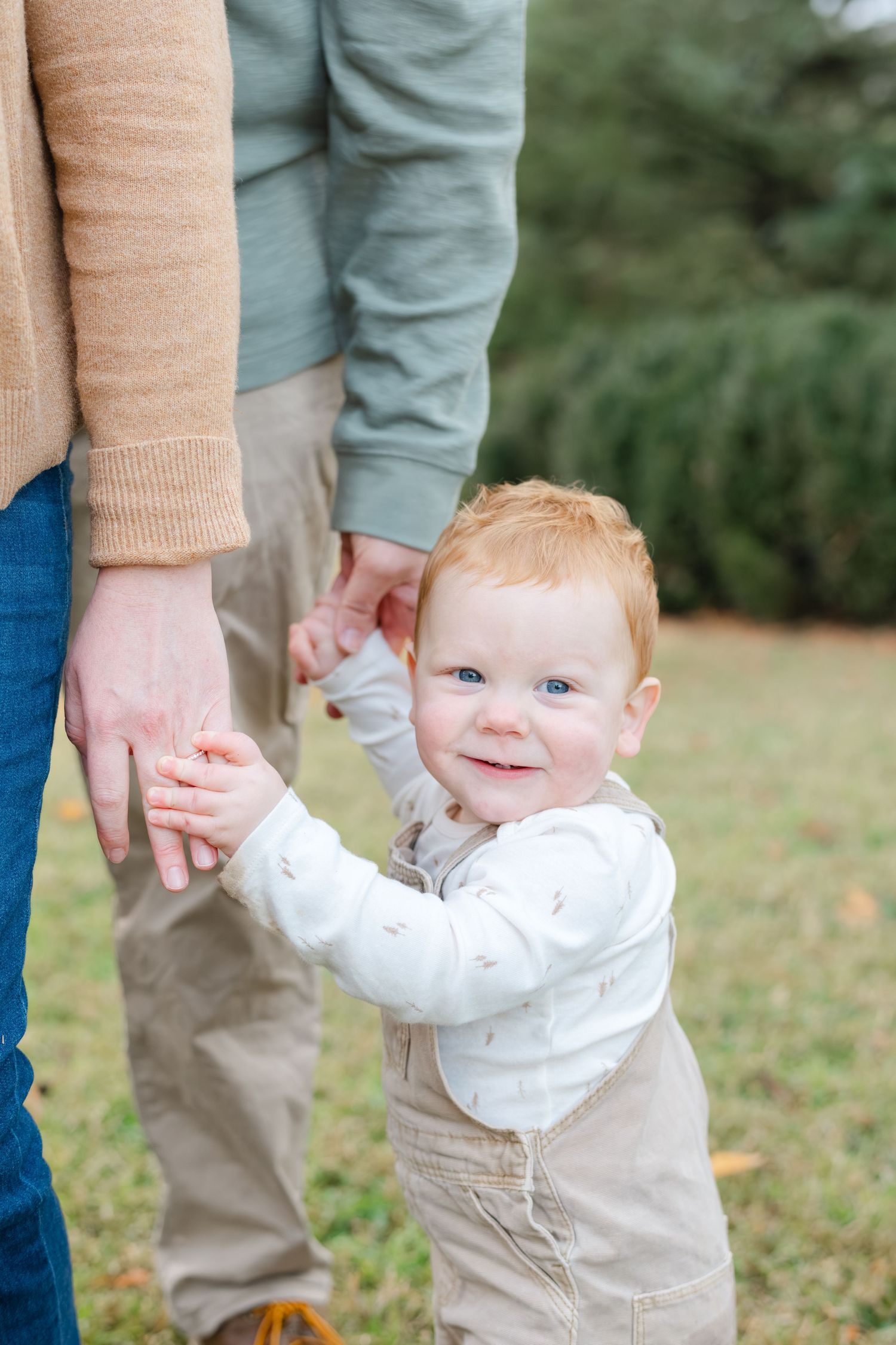A series of photos showing a baby in white shirt and khaki pants holding onto an adult's hands while standing outdoors.