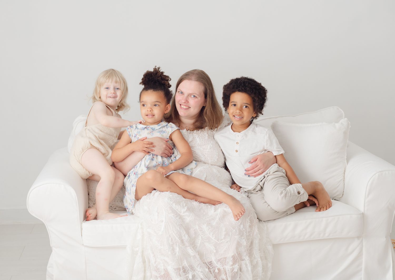 People relaxing together on a cozy white couch in matching light-colored outfits.
