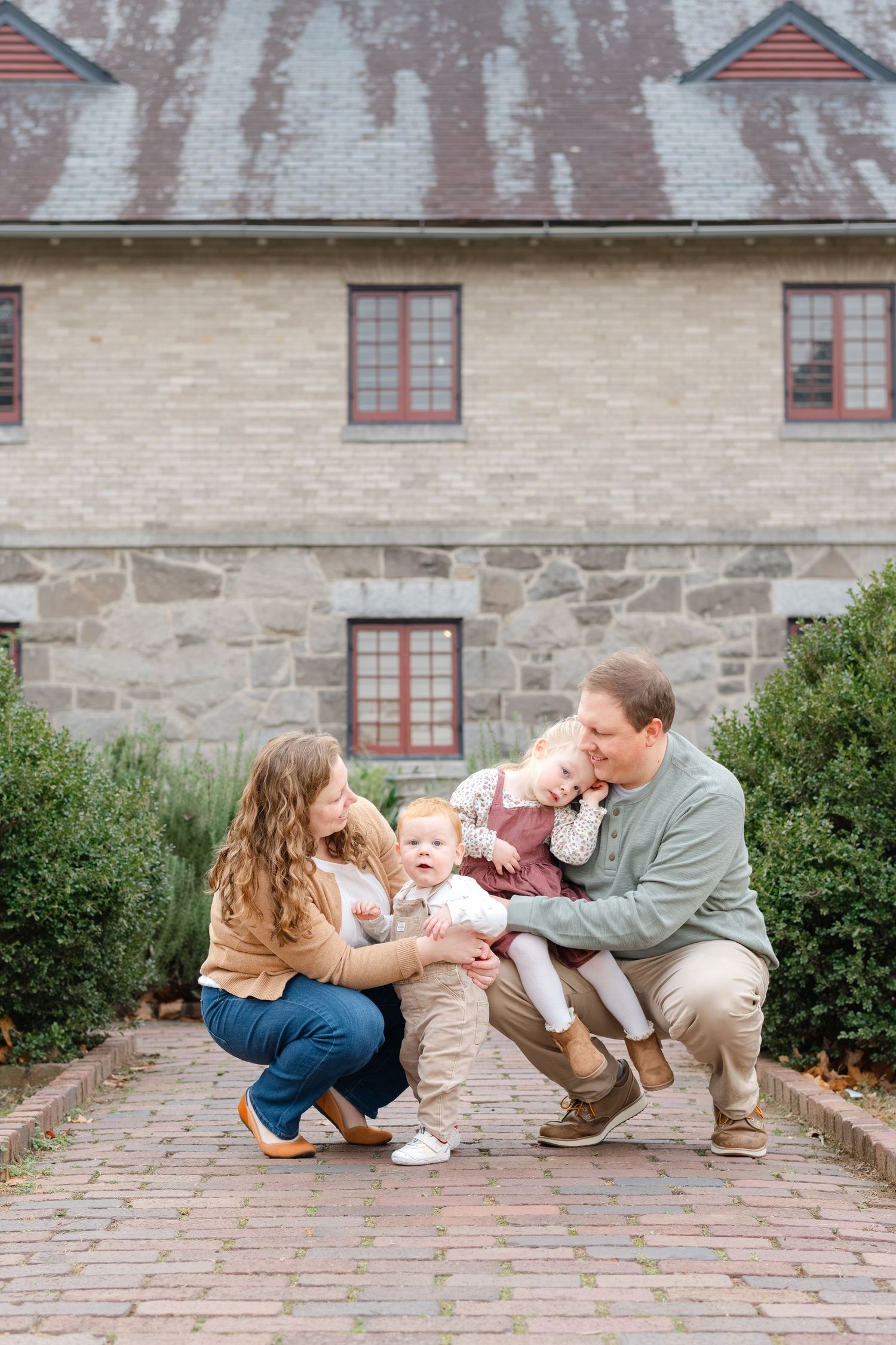 A family shares a playful moment together on a stone patio outside a historic building.