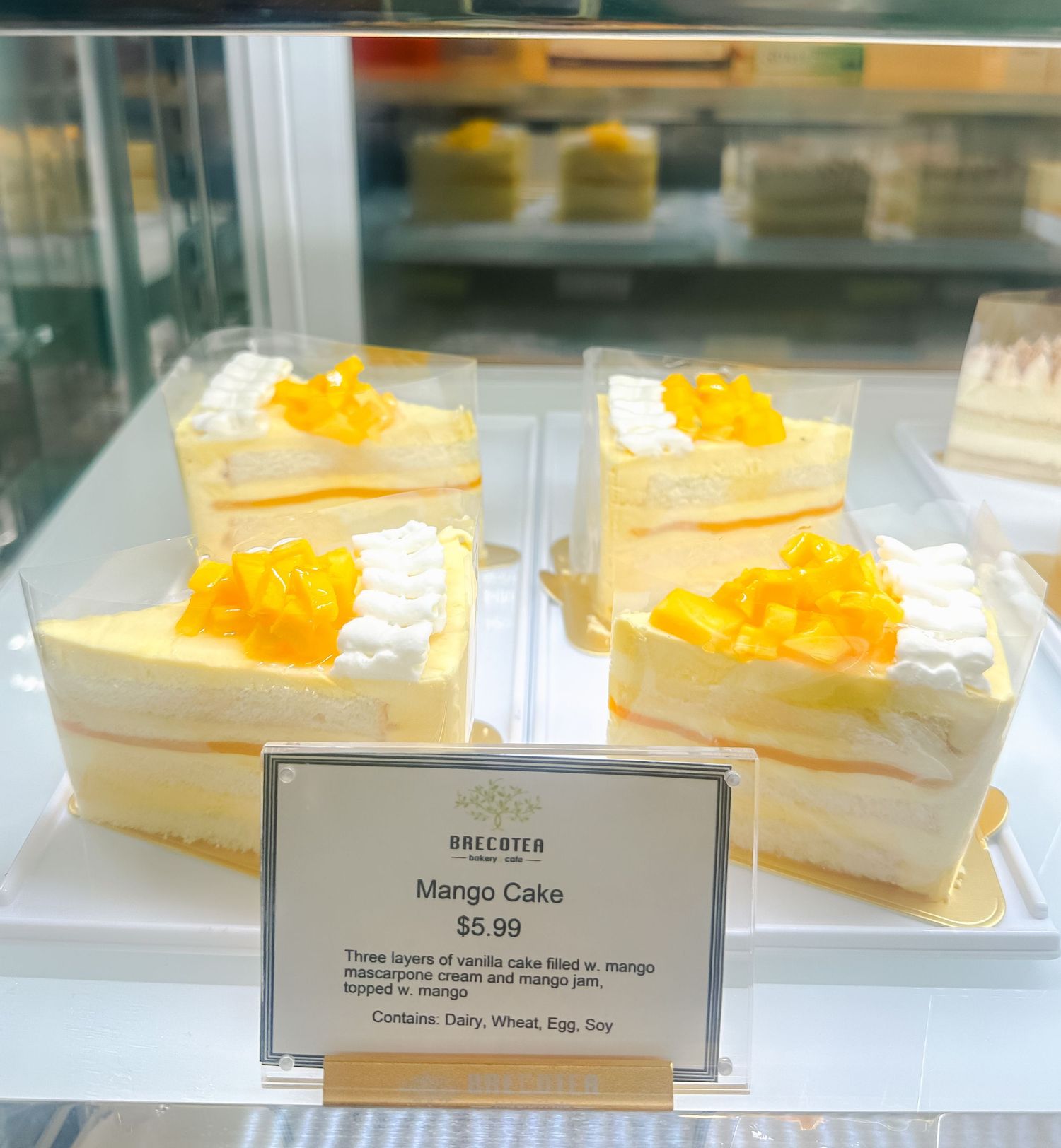 Close-up of yellow custard desserts in a glass bakery display case with price tags.