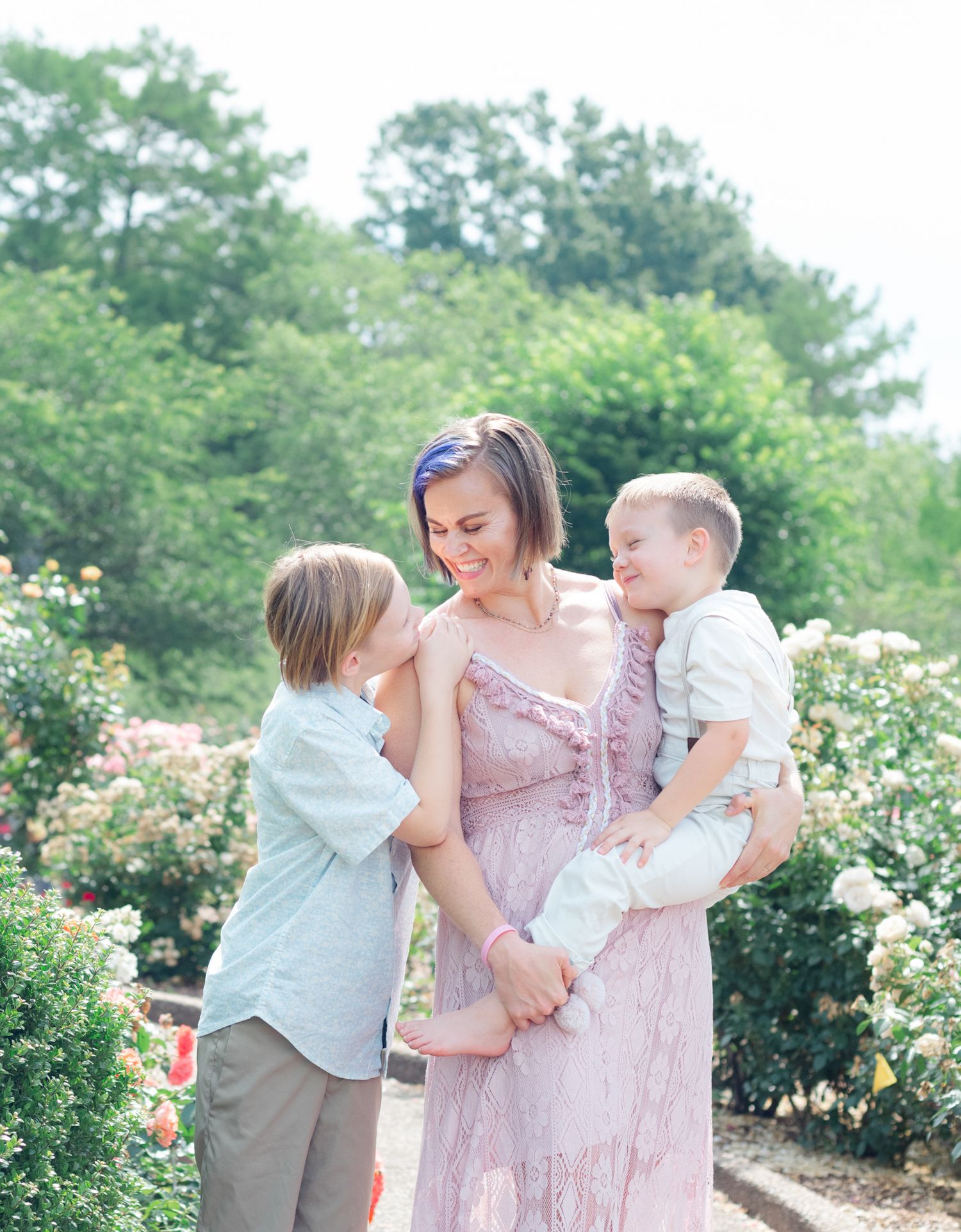 Family sharing playful moment together in blooming rose garden.