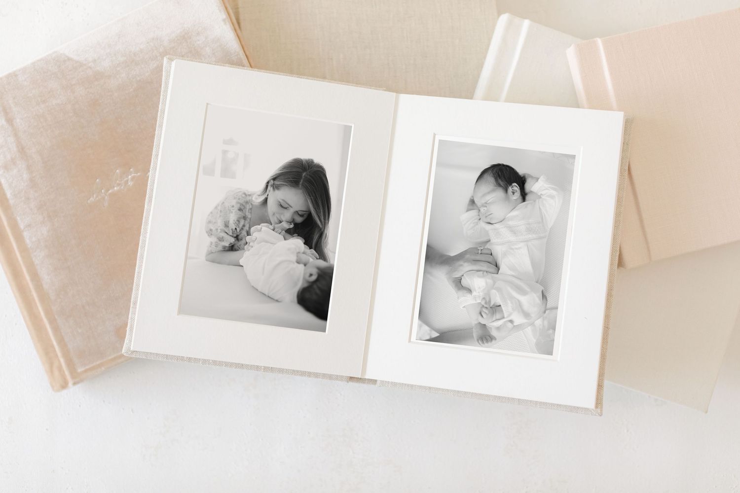 Open photo album displaying two black and white newborn portraits of parents tenderly holding their baby.