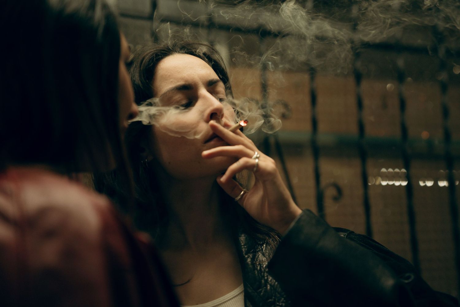 A cinematic street scene shows shadowy figures in dramatic low lighting against brick walls.