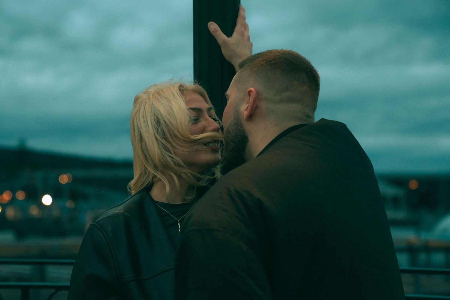 A couple embraces while looking out over a city skyline at dusk with twinkling lights in the background.Couple in Bar Harbor Maine