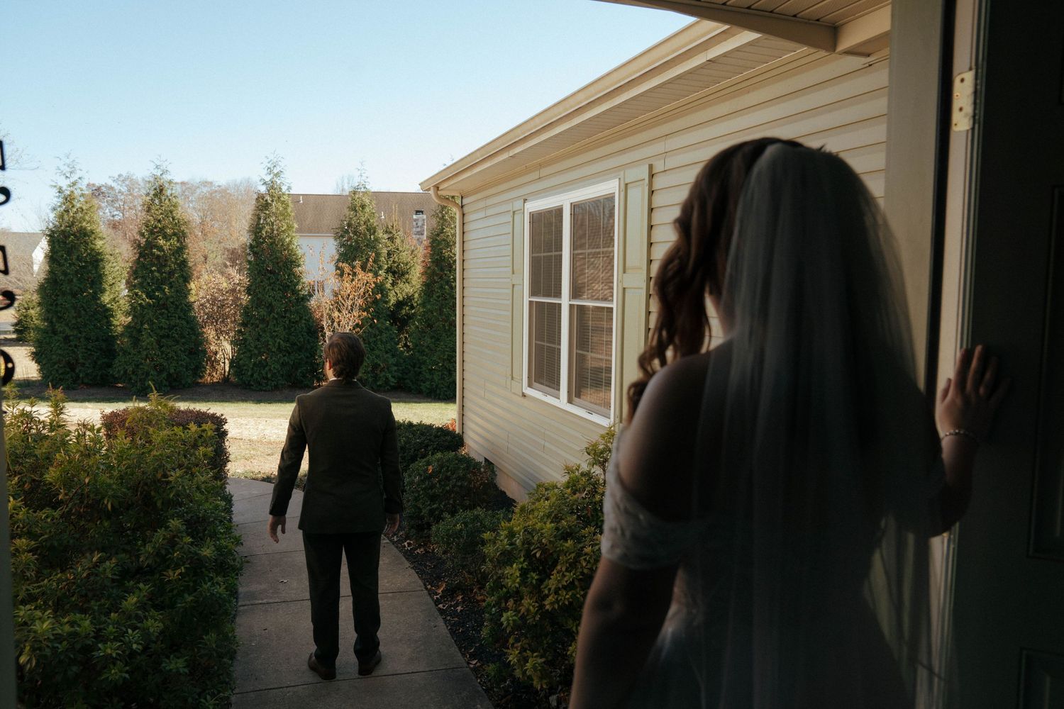 Silhouetted figures looking out doorway on wedding day.
