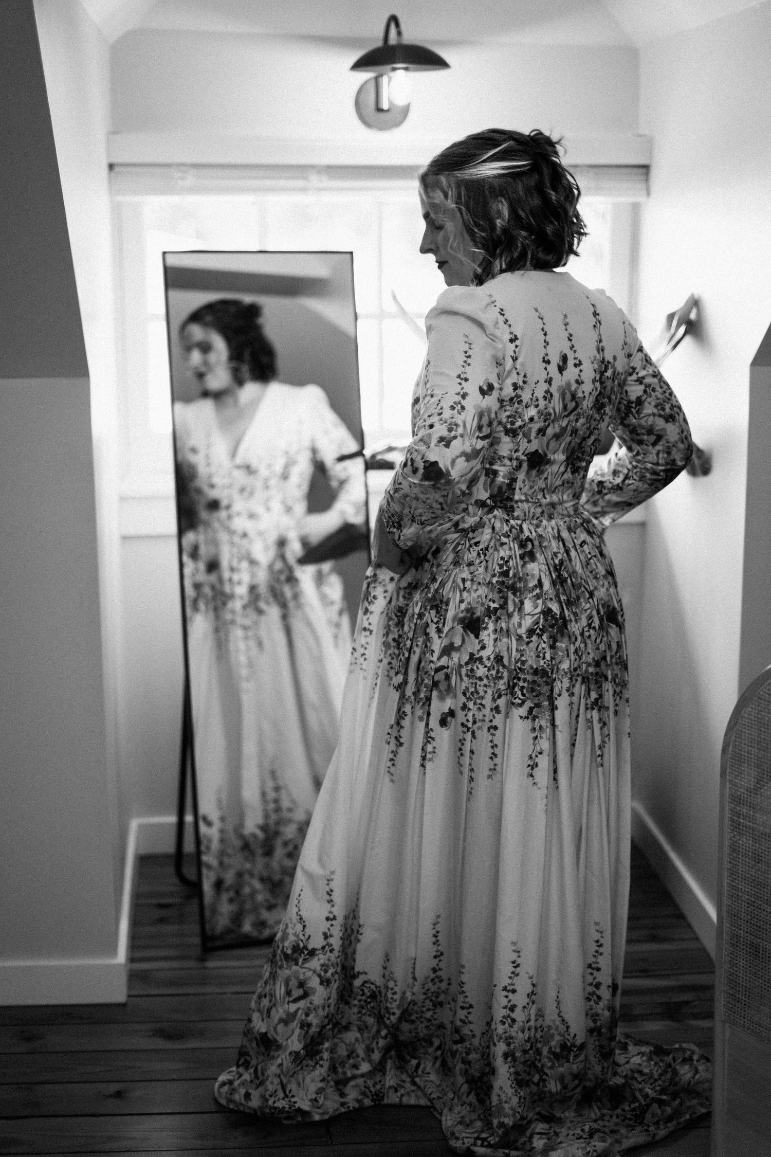 A floral embroidered dress is reflected in a mirror showing delicate details.