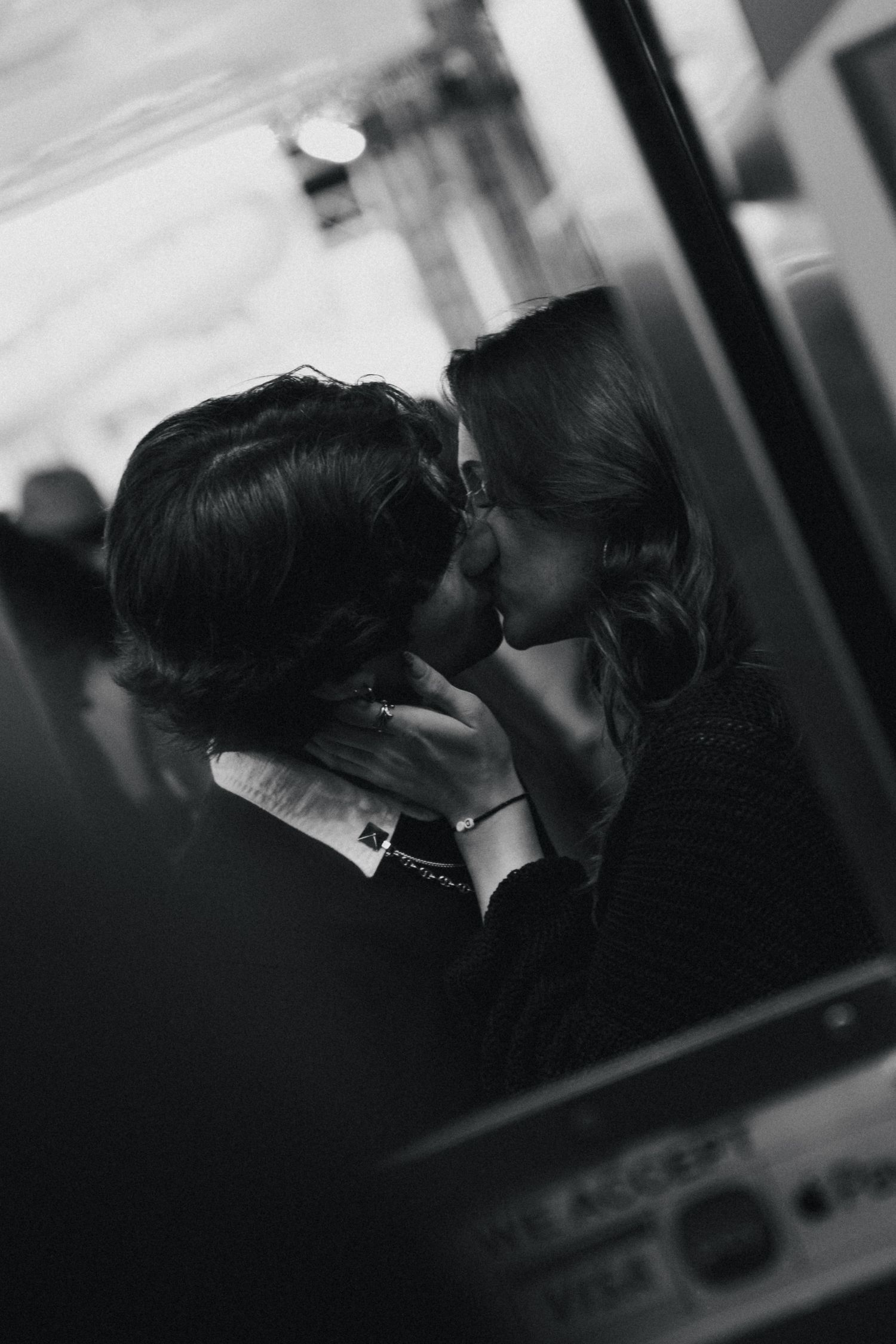 Black and white photo of two people kissing in a romantic moment captured in a reflective surface. Couple in San Diego California.