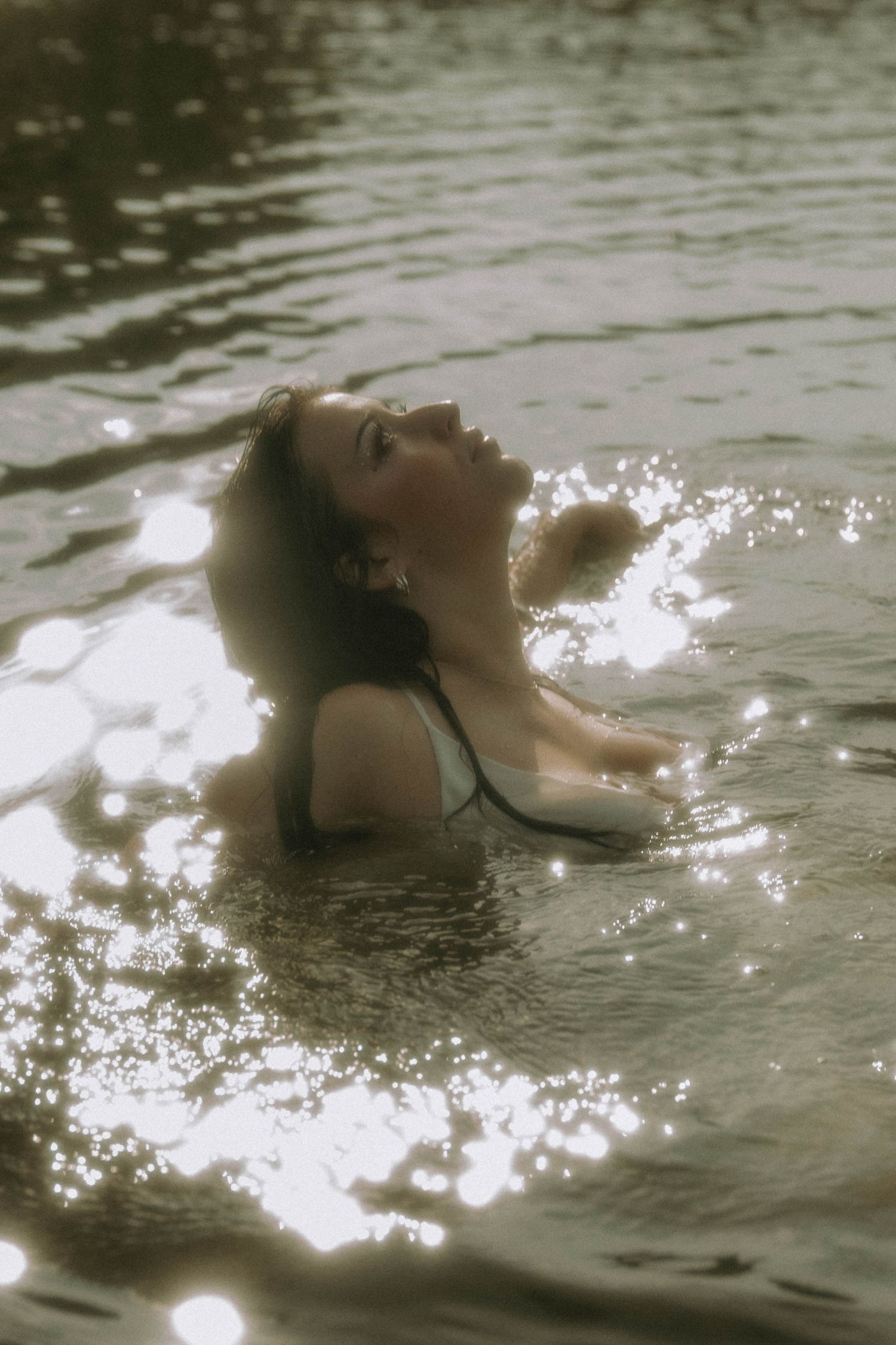 Dreamy portrait of someone floating in sparkling water with a vintage effect.