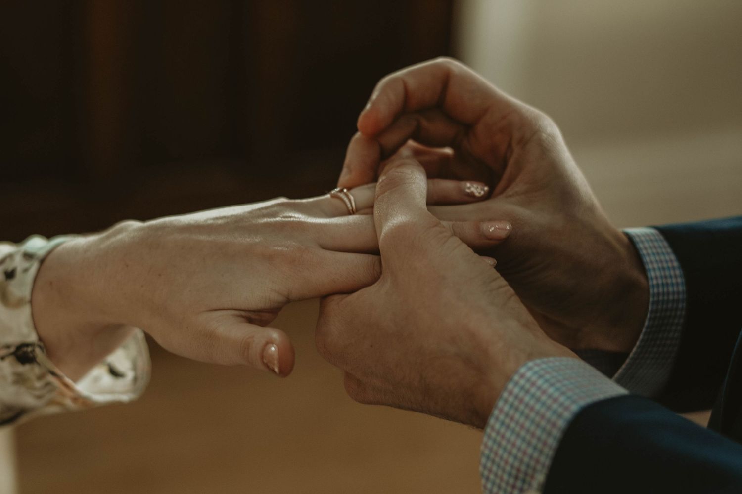 Close-up shot of hands exchanging a ring during an intimate moment.